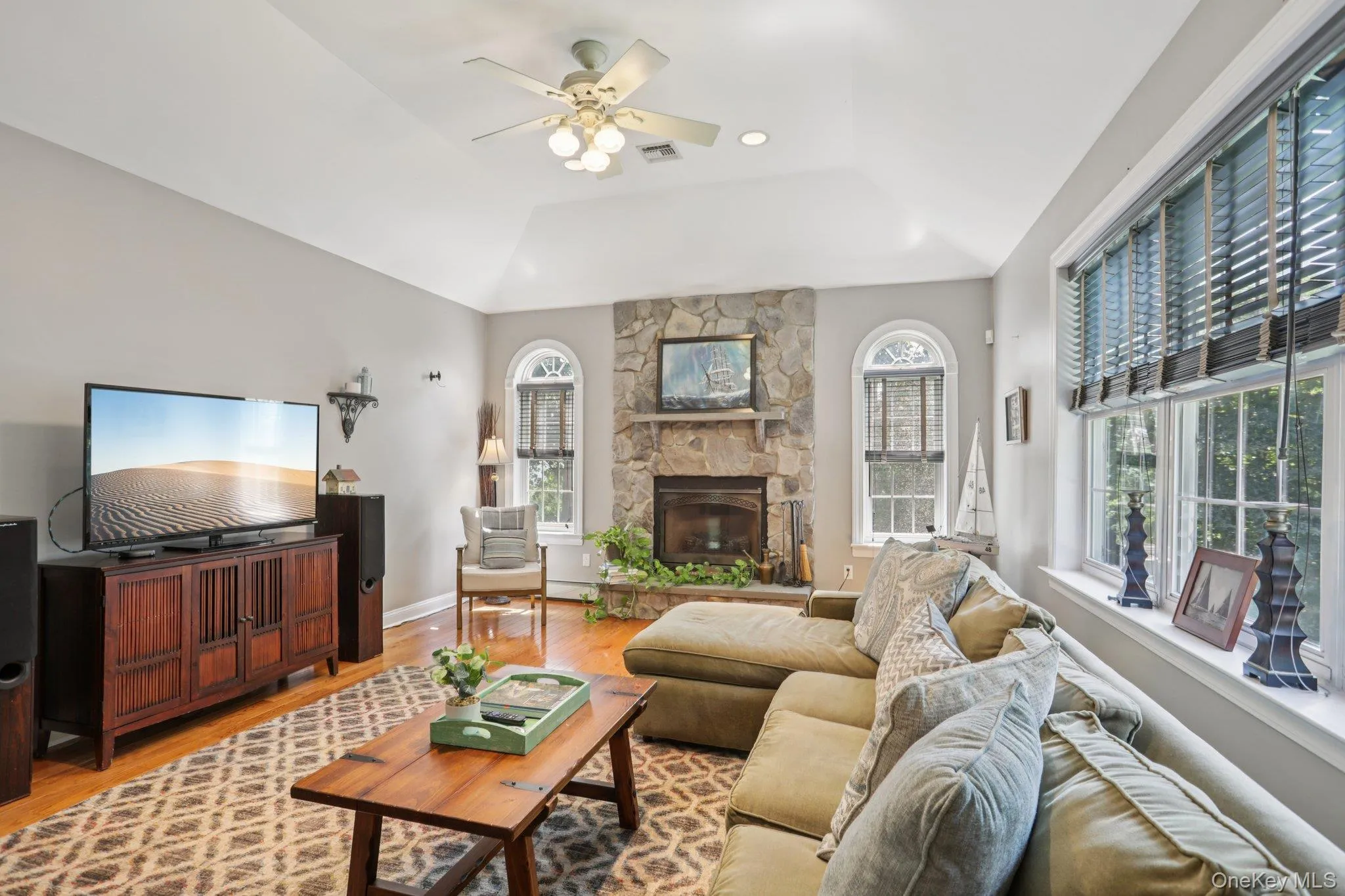 Living area with wood finished floors, a fireplace, a ceiling fan, and a raised ceiling Living area with wood finished floors, a fireplace, a ceiling fan, and a raised ceiling