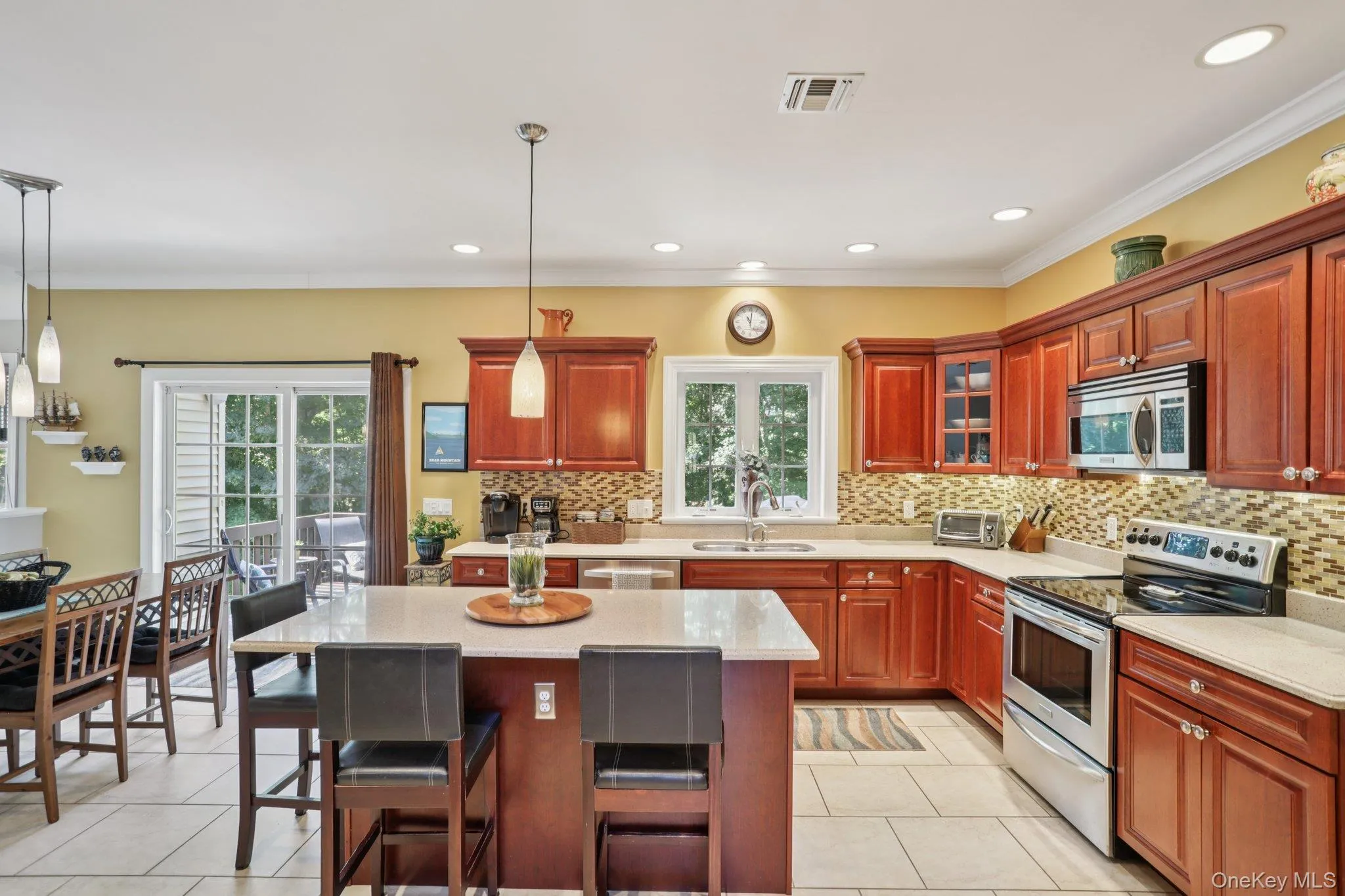 Kitchen featuring stainless steel appliances, a center island, light tile patterned floors, backsplash, and a kitchen breakfast bar Kitchen featuring stainless steel appliances, a center island, light tile patterned floors, backsplash, and a kitchen breakfast bar