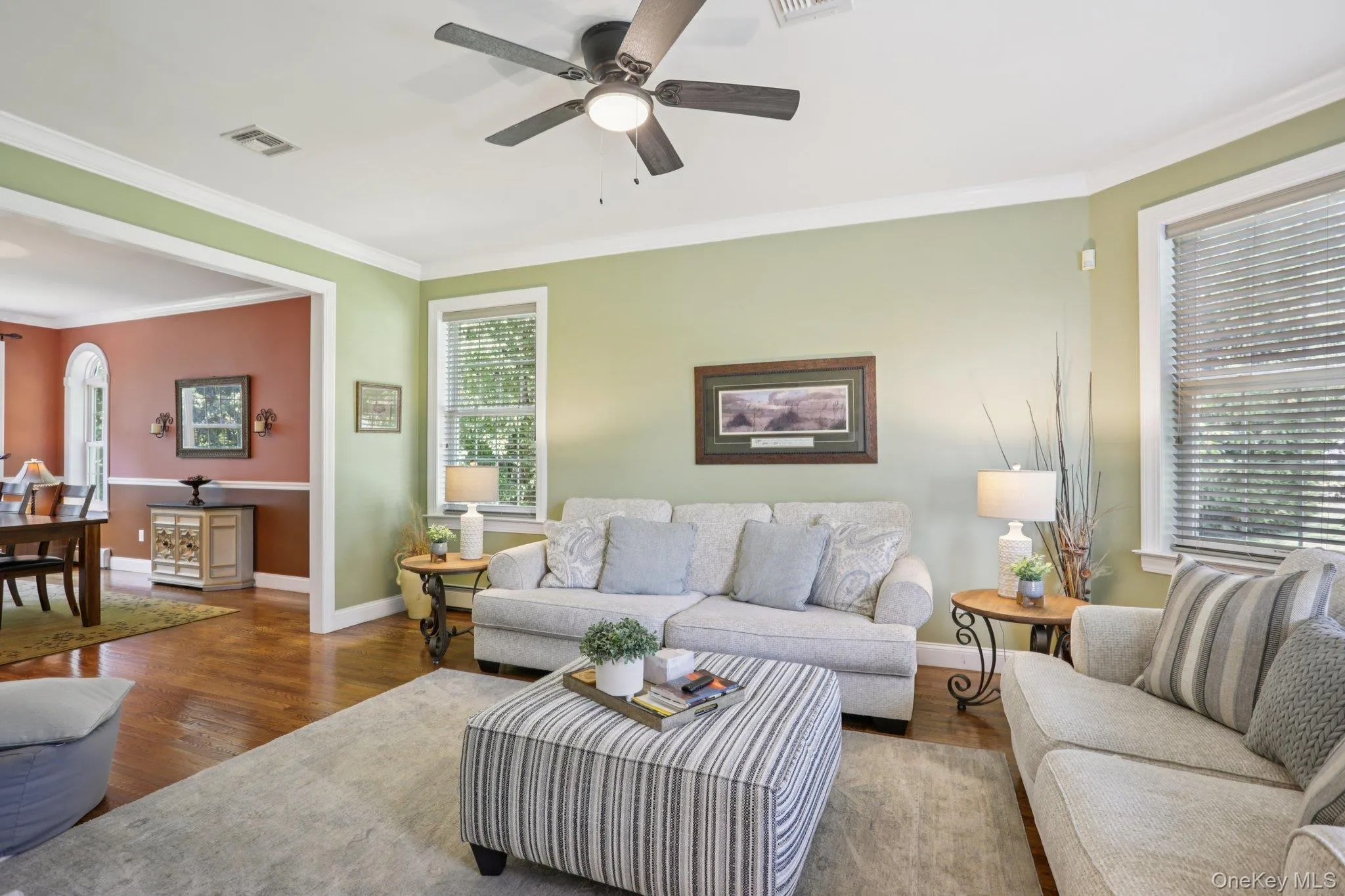 Living area featuring ornamental molding, wood finished floors, plenty of natural light, and ceiling fan Living area featuring ornamental molding, wood finished floors, plenty of natural light, and ceiling fan