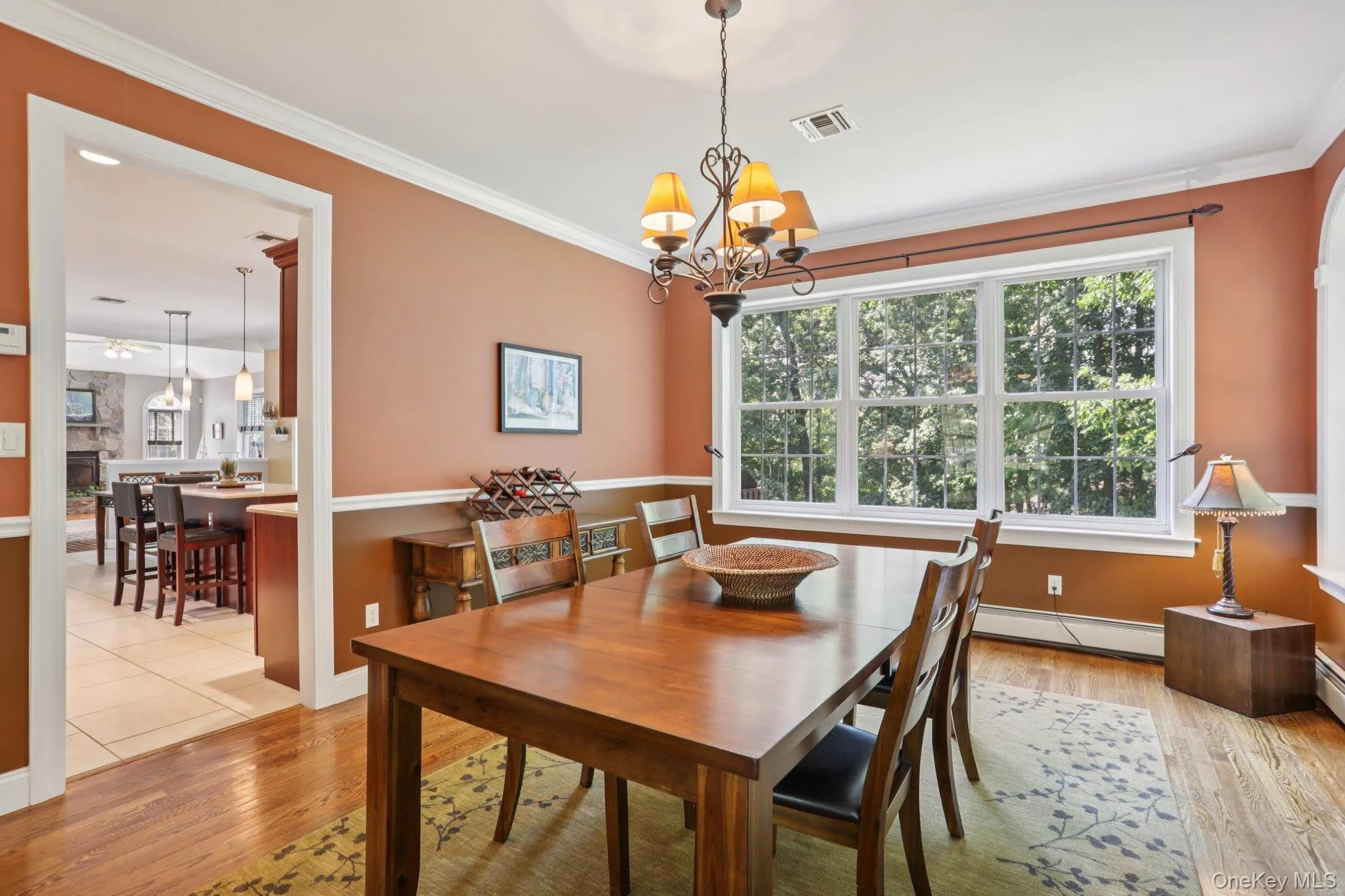 Dining room with ornamental molding, light wood-type flooring, a chandelier, and a baseboard radiator Dining room with ornamental molding, light wood-type flooring, a chandelier, and a baseboard radiator