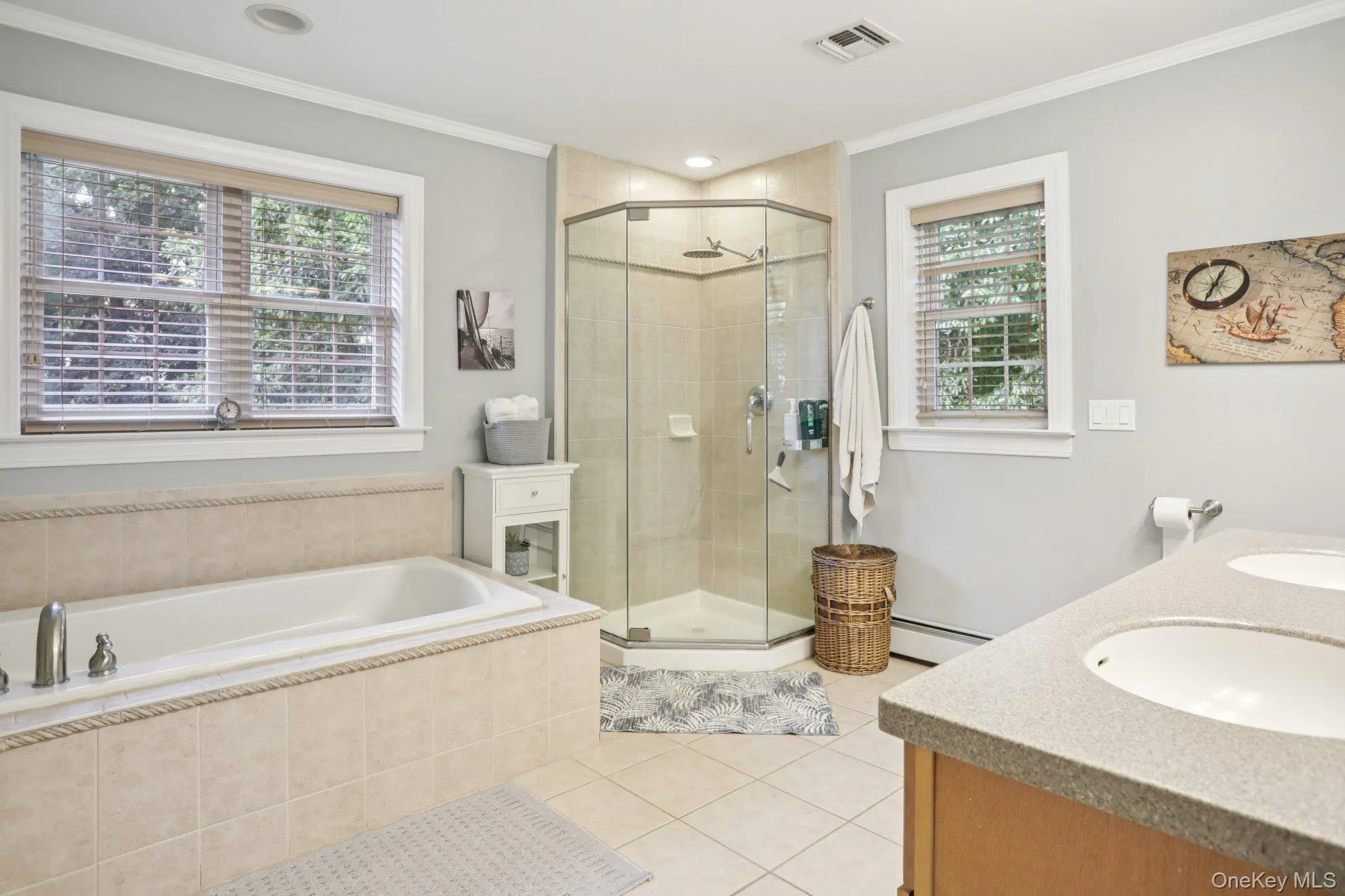 Full bathroom featuring a bath, a shower stall, light tile patterned floors, double vanity, and crown molding Full bathroom featuring a bath, a shower stall, light tile patterned floors, double vanity, and crown molding