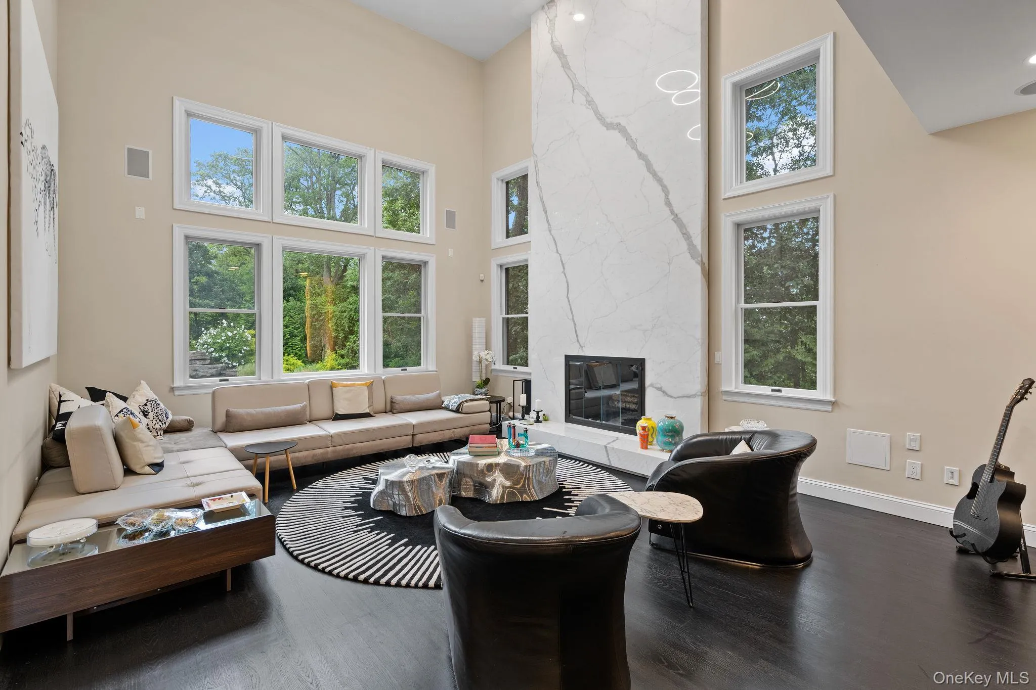 Living room featuring a high ceiling, dark wood-type flooring, and a high end fireplace Living room featuring a high ceiling, dark wood-type flooring, and a high end fireplace