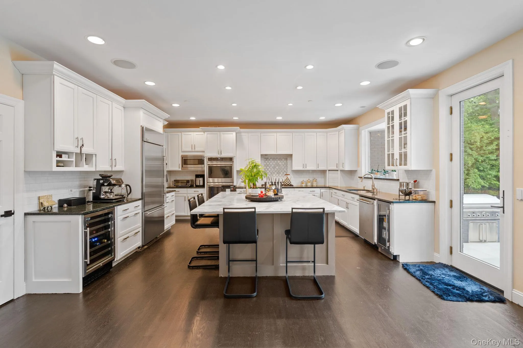 Kitchen featuring a kitchen breakfast bar, decorative backsplash, white cabinets, dark wood finished floors, and recessed lighting Kitchen featuring a kitchen breakfast bar, decorative backsplash, white cabinets, dark wood finished floors, and recessed lighting