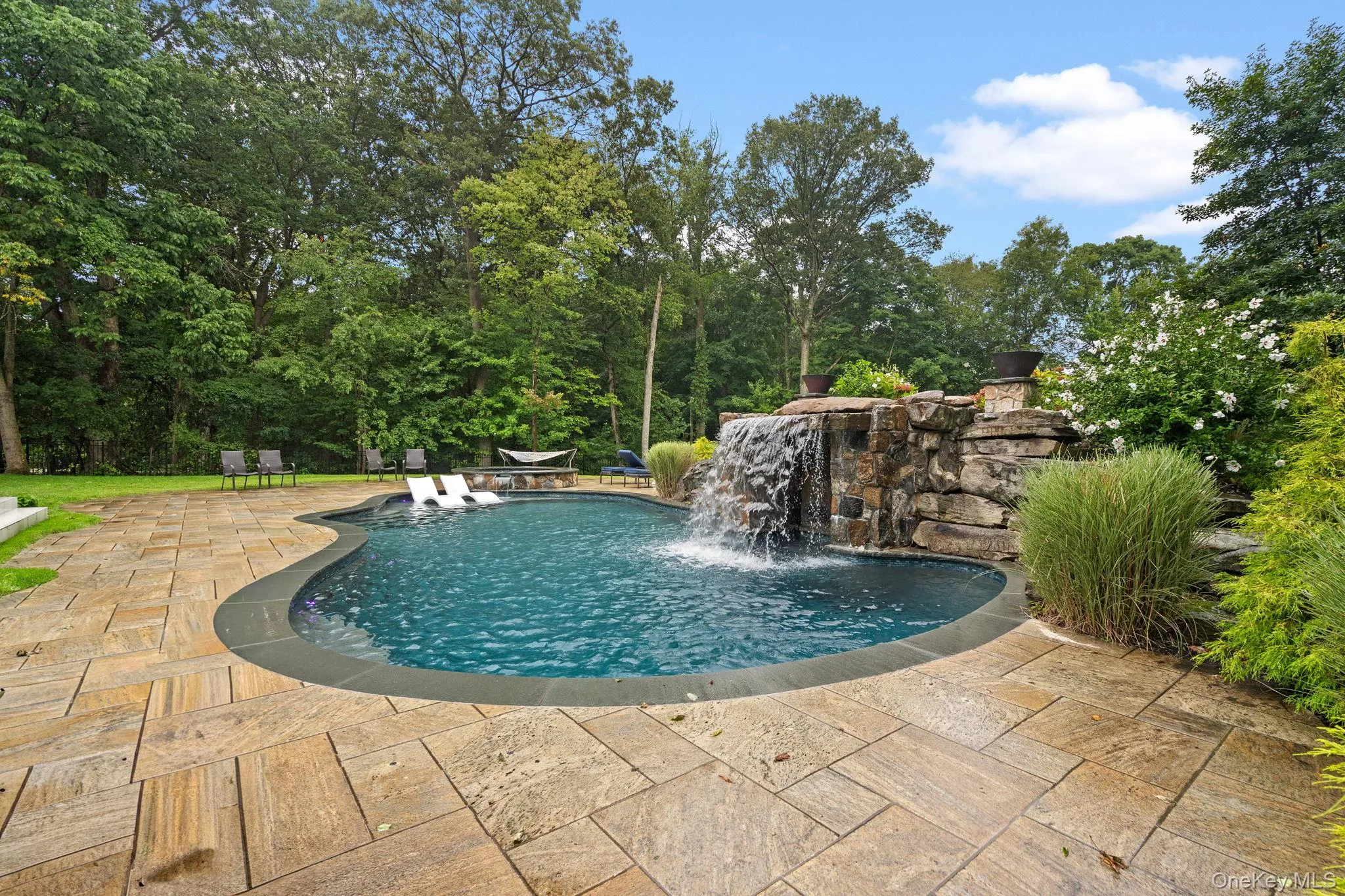 Swimming pool with a patio area and view of scattered trees Swimming pool with a patio area and view of scattered trees
