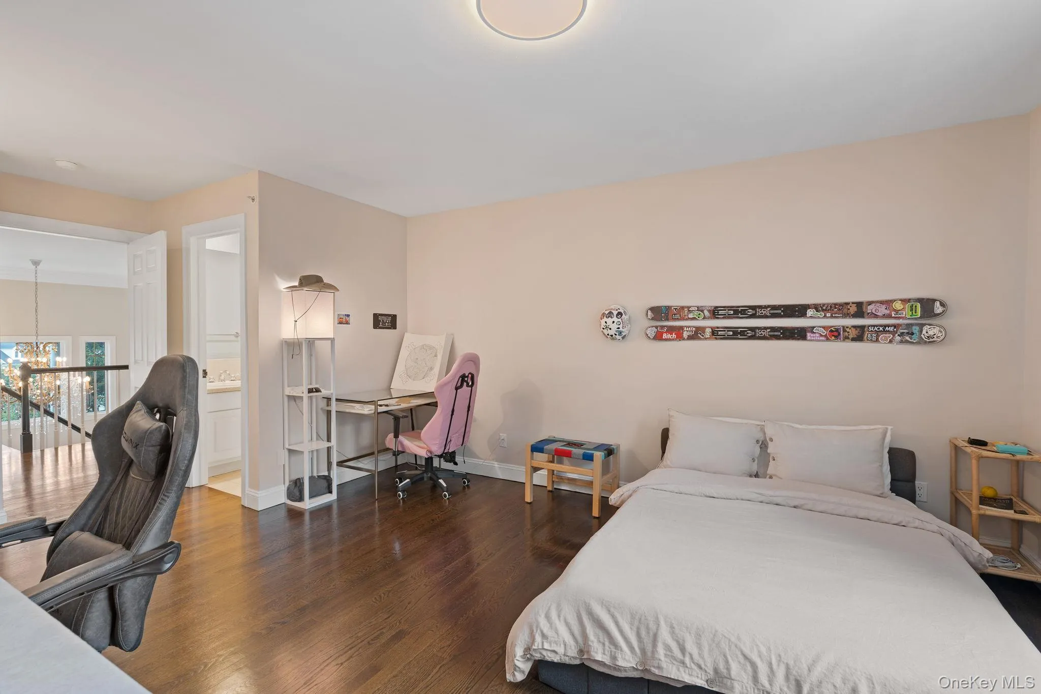 Bedroom with an office area, dark wood finished floors, a chandelier, and ensuite bathroom Bedroom with an office area, dark wood finished floors, a chandelier, and ensuite bathroom
