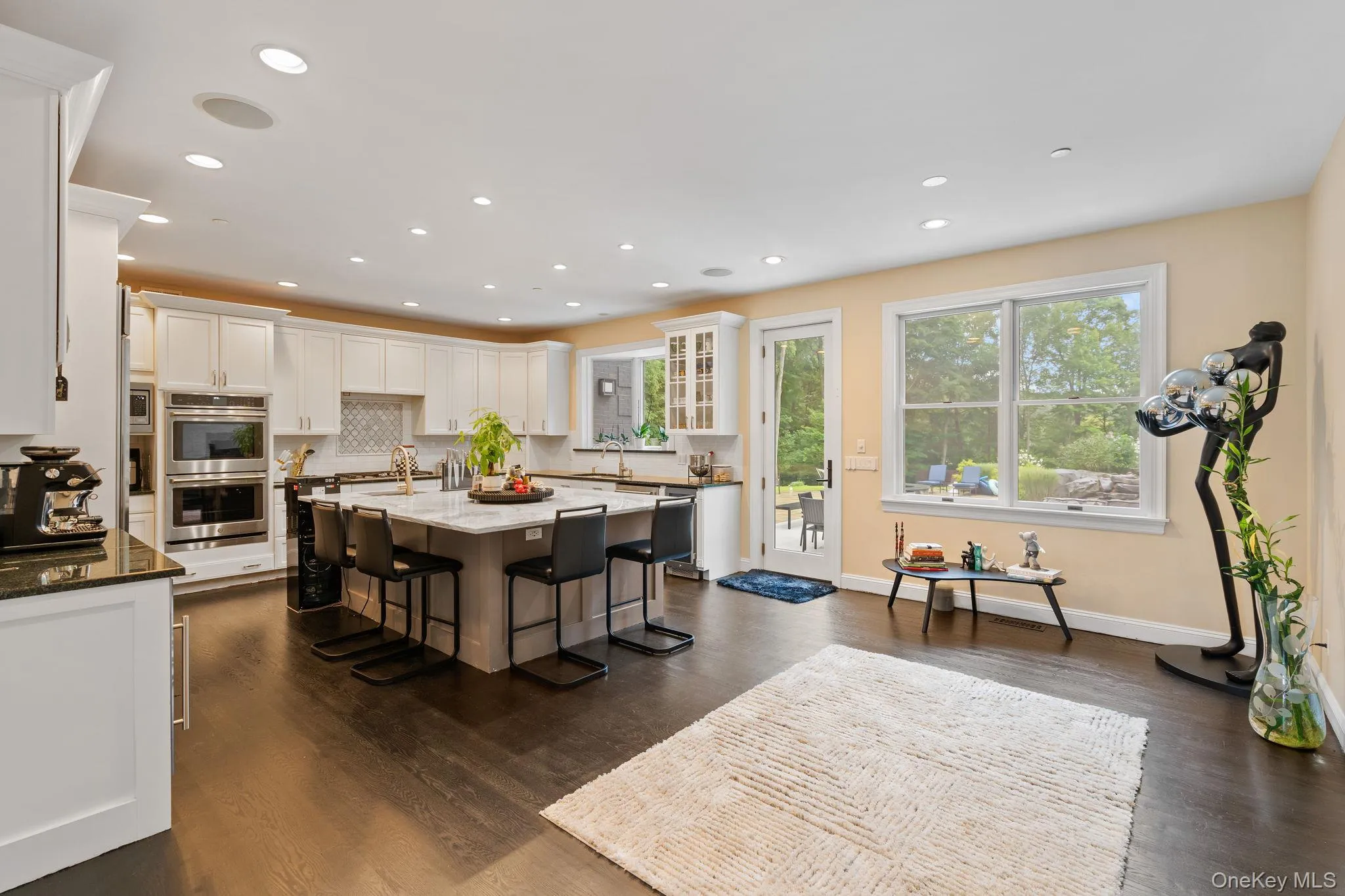 Kitchen featuring a breakfast bar, light stone counters, white cabinetry, dark wood-style flooring, and a kitchen island Kitchen featuring a breakfast bar, light stone counters, white cabinetry, dark wood-style flooring, and a kitchen island