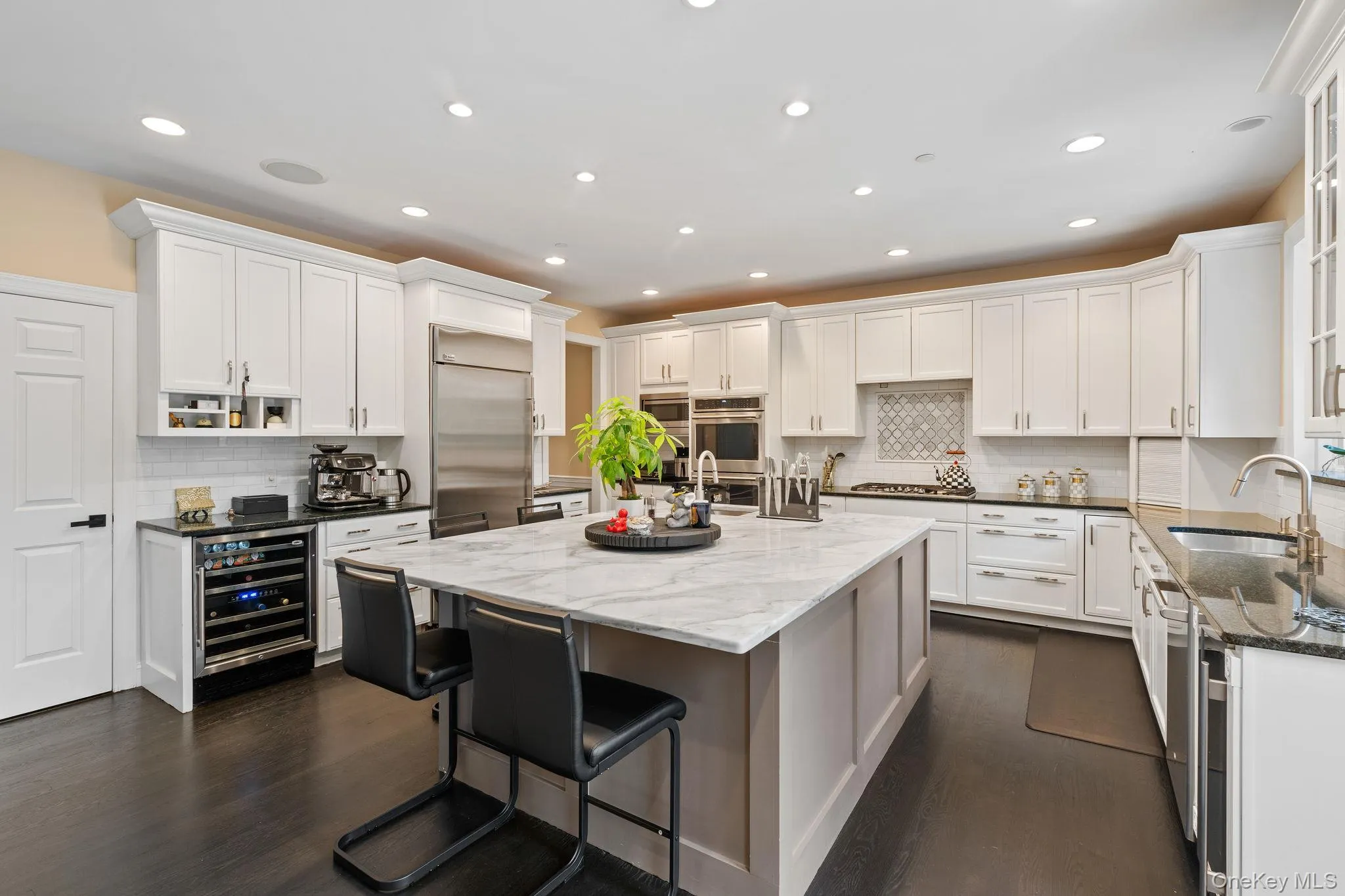 Kitchen with dark stone counters, tasteful backsplash, dark wood-type flooring, white cabinets, and recessed lighting Kitchen with dark stone counters, tasteful backsplash, dark wood-type flooring, white cabinets, and recessed lighting