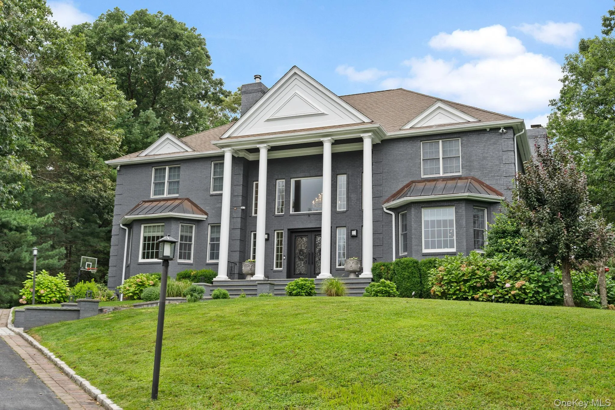 Greek revival inspired property with a chimney, a standing seam roof, a front yard, and brick siding Greek revival inspired property with a chimney, a standing seam roof, a front yard, and brick siding