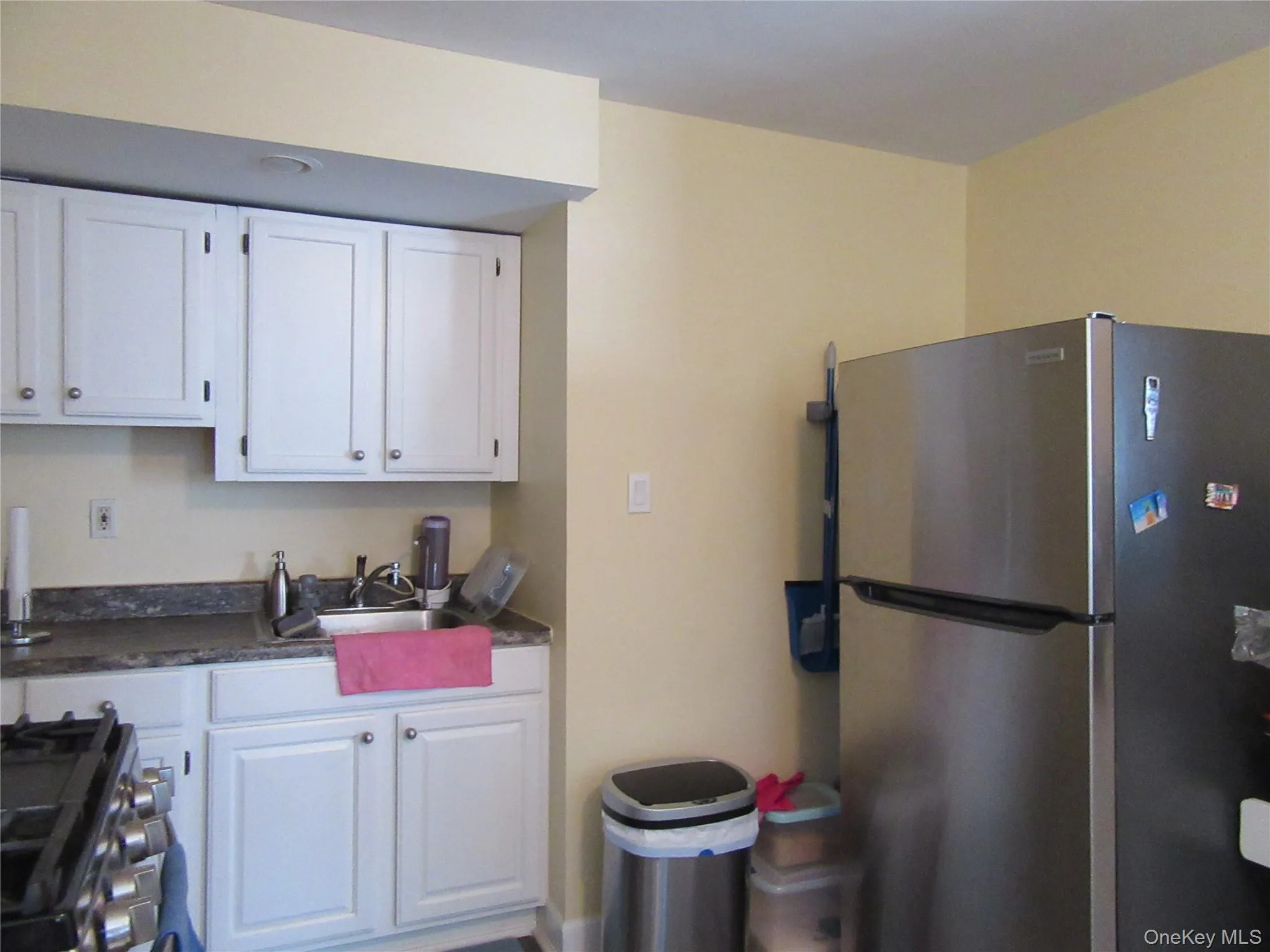Kitchen featuring freestanding refrigerator, white cabinets, gas range, and dark stone countertops Kitchen featuring freestanding refrigerator, white cabinets, gas range, and dark stone countertops