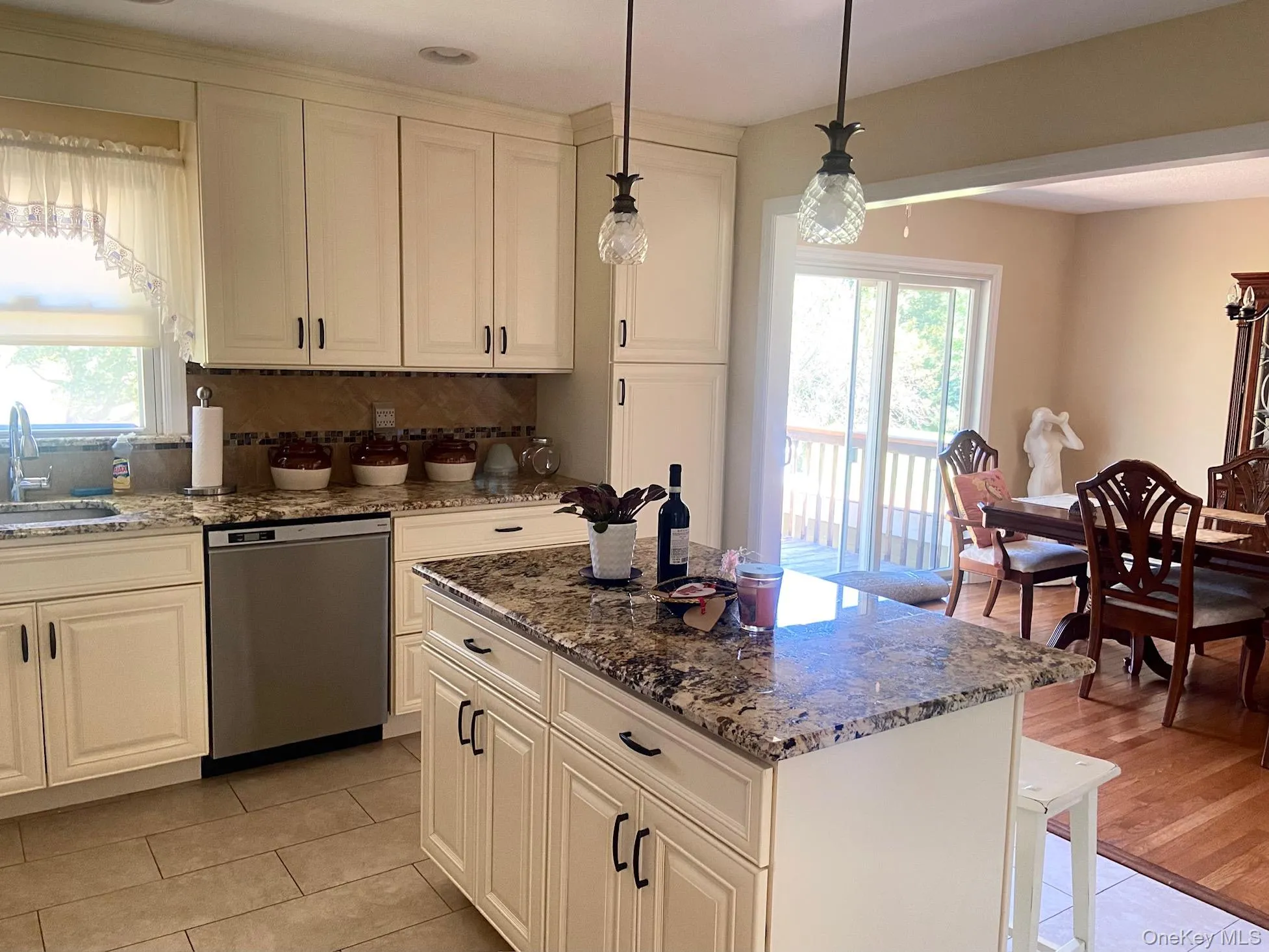 Kitchen with dark stone counters, stainless steel dishwasher, backsplash, and a center island Kitchen with dark stone counters, stainless steel dishwasher, backsplash, and a center island