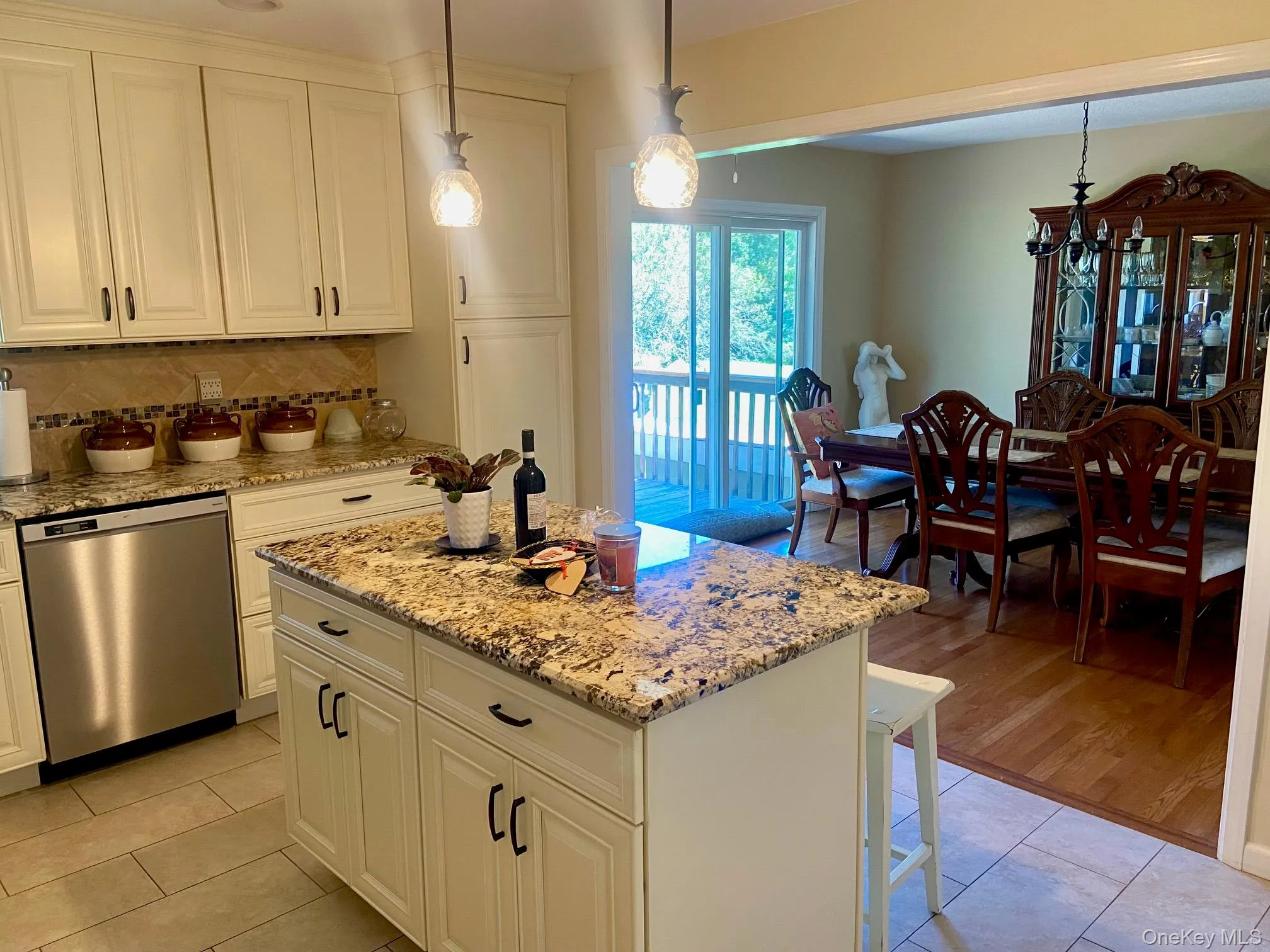 Kitchen featuring pendant lighting, light stone counters, and decorative backsplash Kitchen featuring pendant lighting, light stone counters, and decorative backsplash