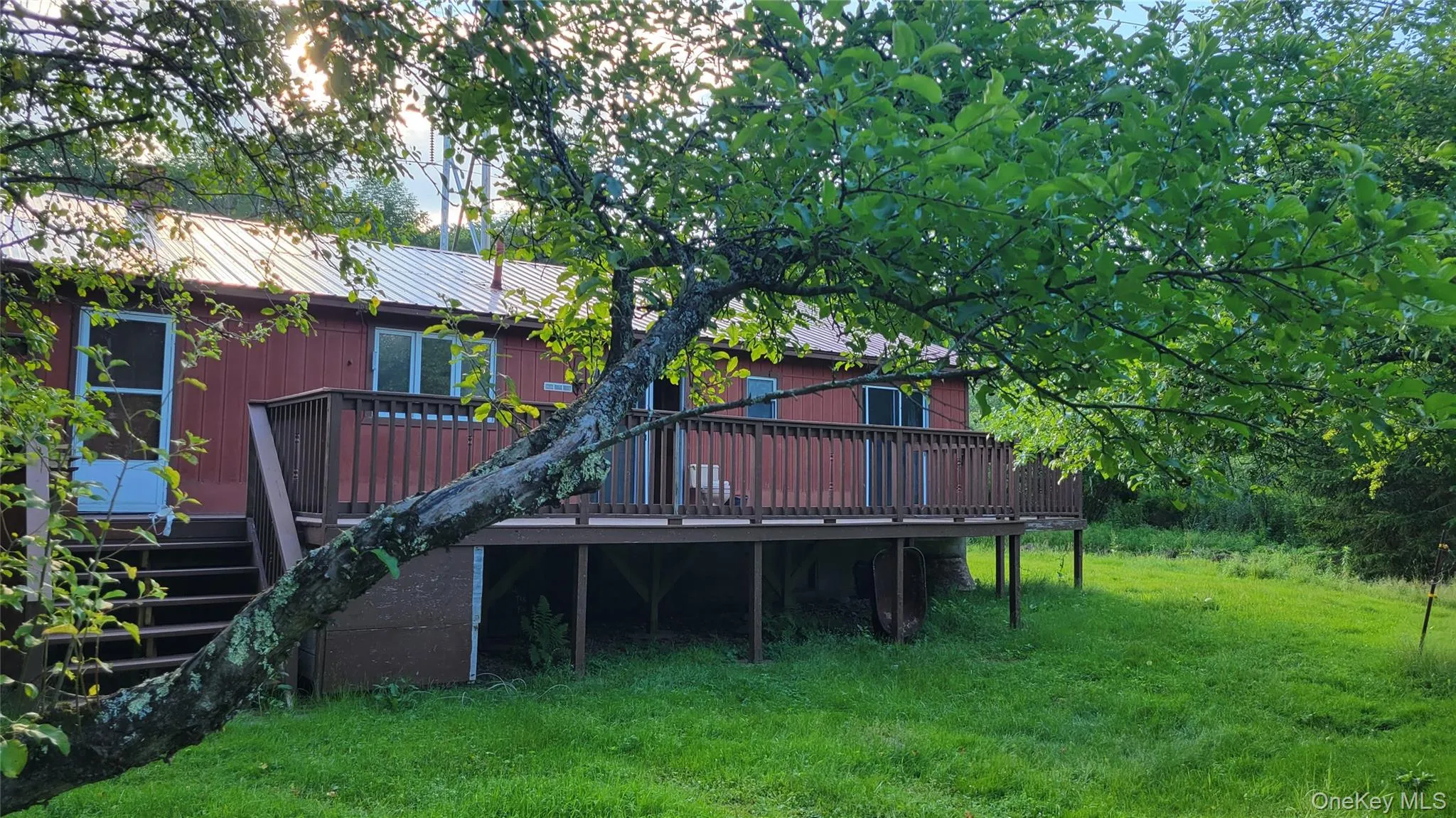 Back of house with a wooden deck, a metal roof, and a yard Back of house with a wooden deck, a metal roof, and a yard