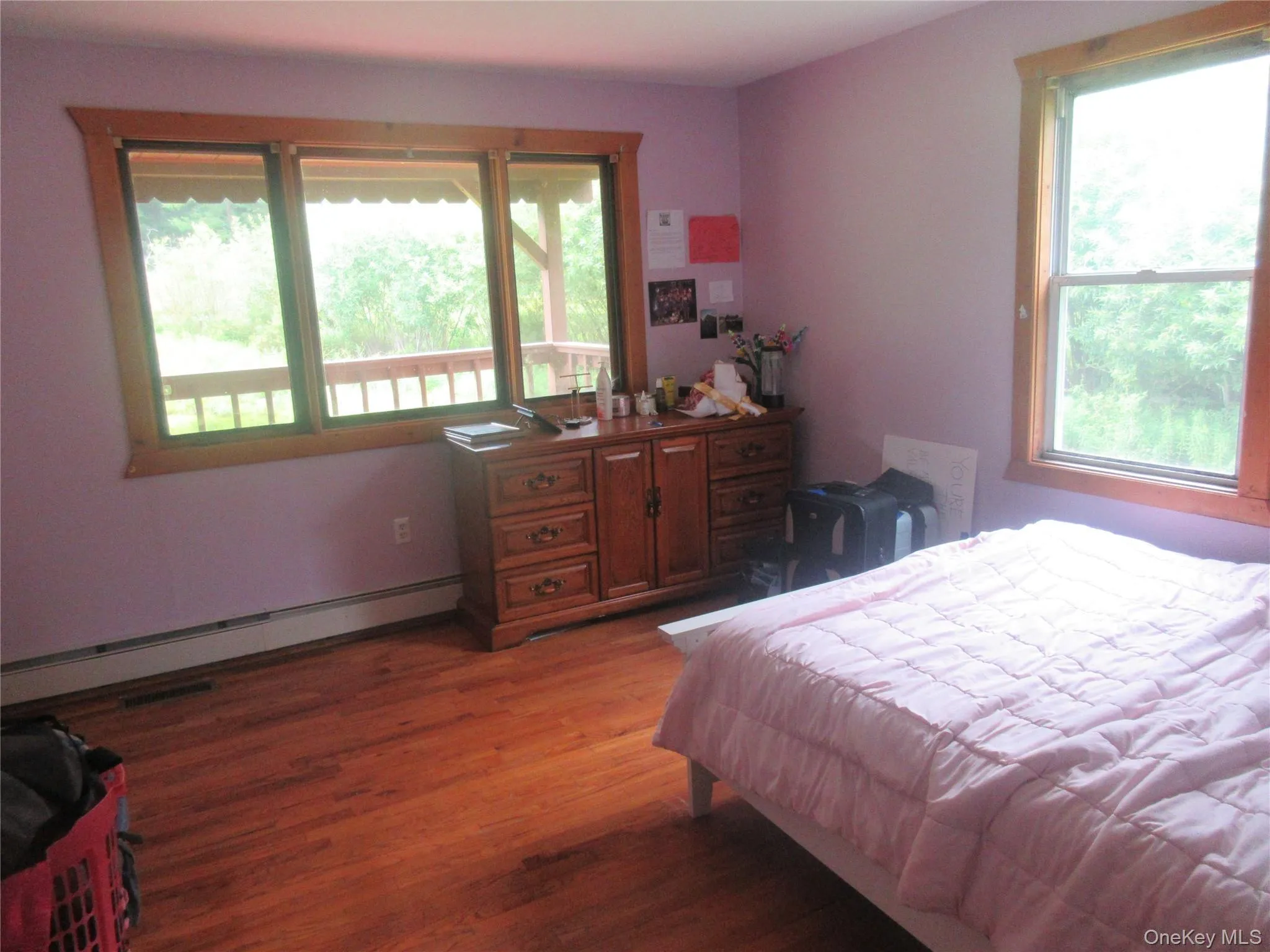 Bedroom with wood finished floors, baseboard heating, and multiple windows Bedroom with wood finished floors, baseboard heating, and multiple windows