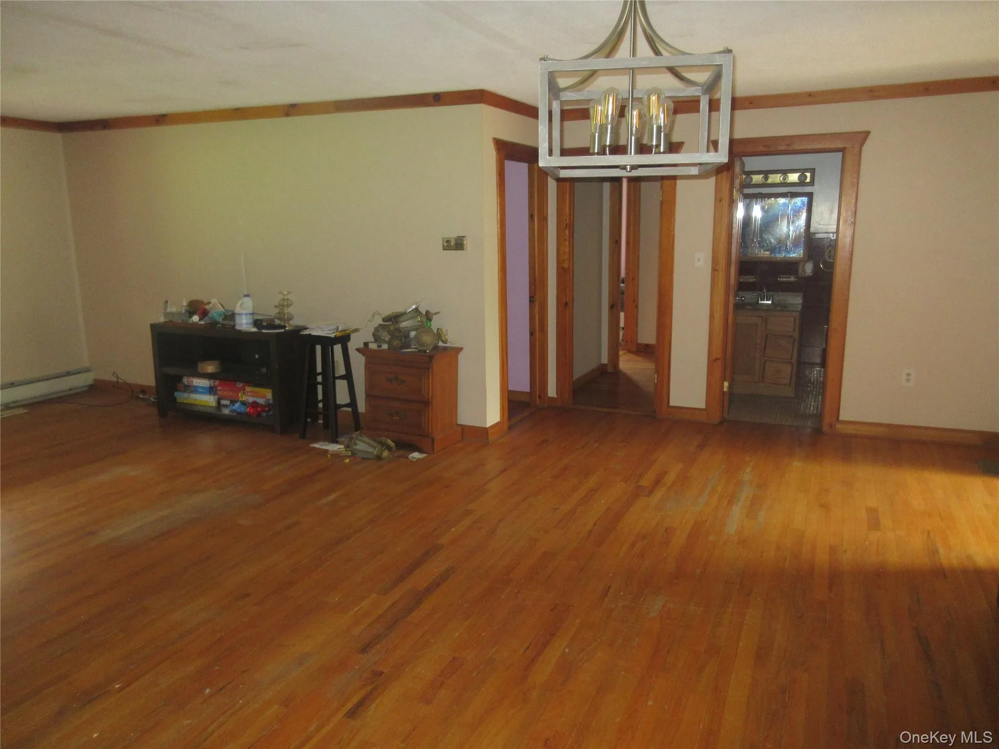 Dining area featuring ornamental molding, wood finished floors, a chandelier, and a baseboard heating unit Dining area featuring ornamental molding, wood finished floors, a chandelier, and a baseboard heating unit