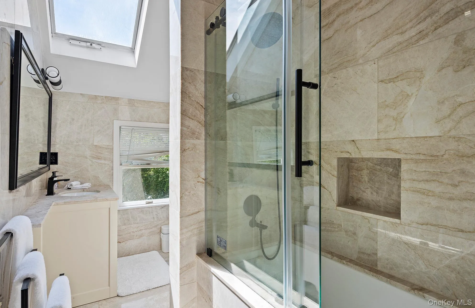 Bathroom featuring tiled shower / bath combo, vanity, a skylight, and tile walls Bathroom featuring tiled shower / bath combo, vanity, a skylight, and tile walls
