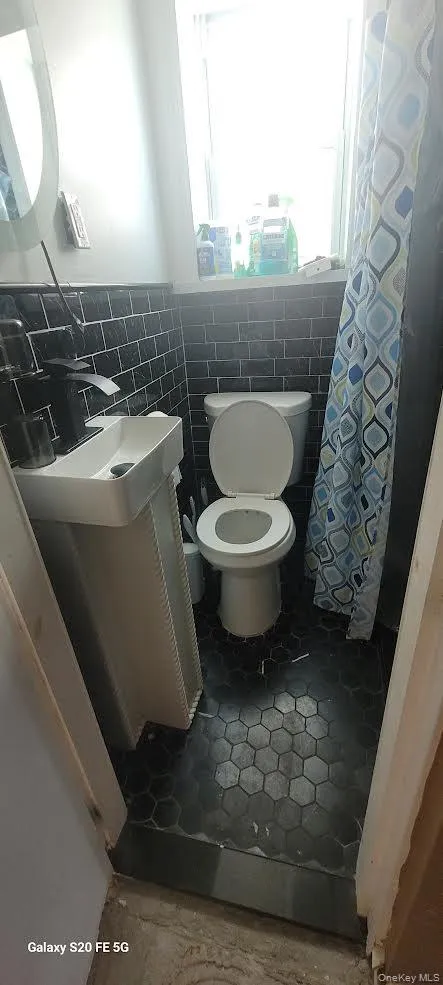 1st Floor full Bathroom featuring toilet and tile walls 1st Floor full Bathroom featuring toilet and tile walls
