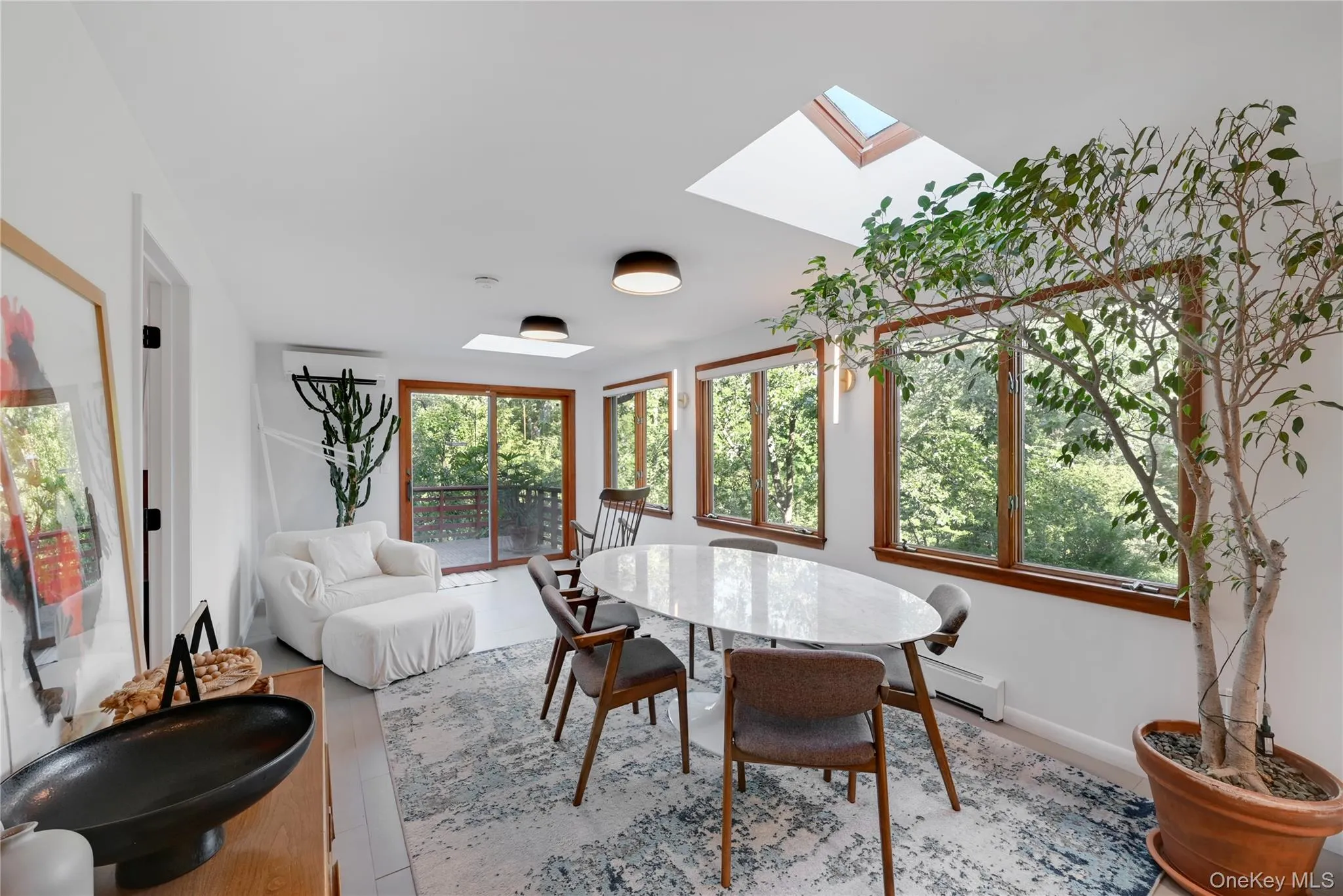 Dining space featuring a skylight, baseboard heating, and wood finished floors Dining space featuring a skylight, baseboard heating, and wood finished floors