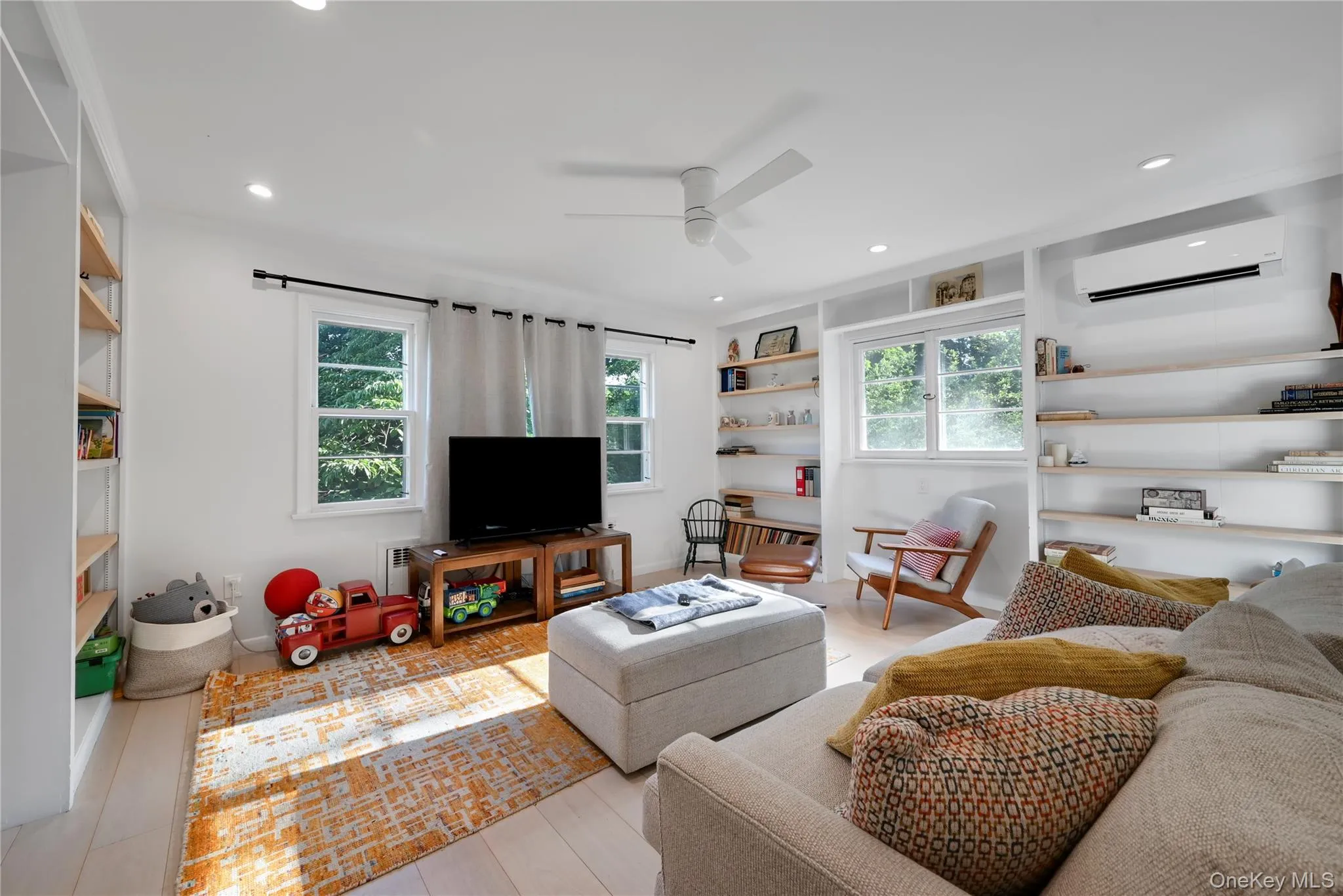 Living area featuring built in shelves, a wall mounted air conditioner, ceiling fan, and recessed lighting Living area featuring built in shelves, a wall mounted air conditioner, ceiling fan, and recessed lighting