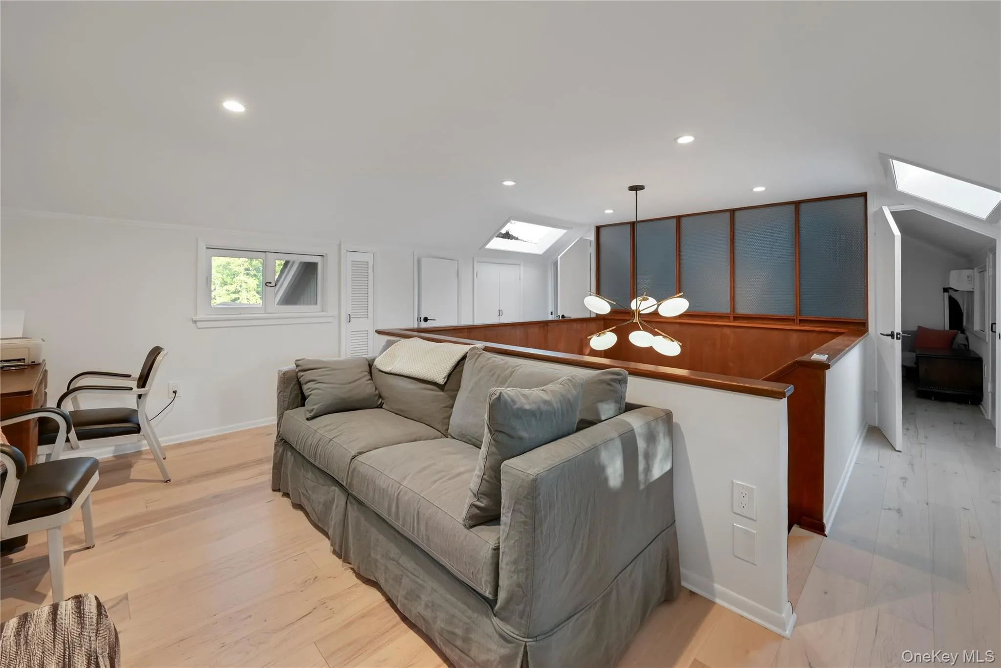 Living room with a skylight, lofted ceiling, light wood-type flooring, recessed lighting, and a chandelier Living room with a skylight, lofted ceiling, light wood-type flooring, recessed lighting, and a chandelier
