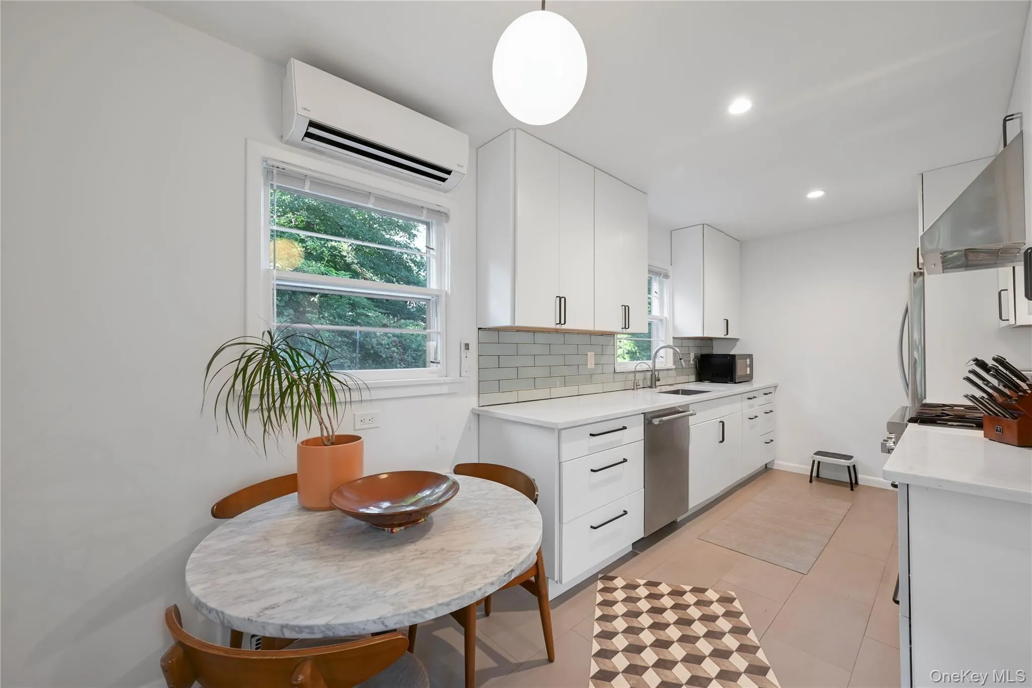 Kitchen featuring light stone counters, a wall mounted air conditioner, backsplash, white cabinetry, and recessed lighting Kitchen featuring light stone counters, a wall mounted air conditioner, backsplash, white cabinetry, and recessed lighting