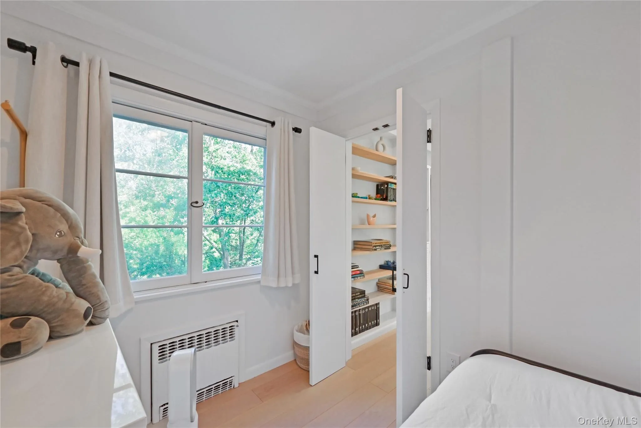 Bedroom with radiator heating unit, crown molding, and light wood-type flooring Bedroom with radiator heating unit, crown molding, and light wood-type flooring