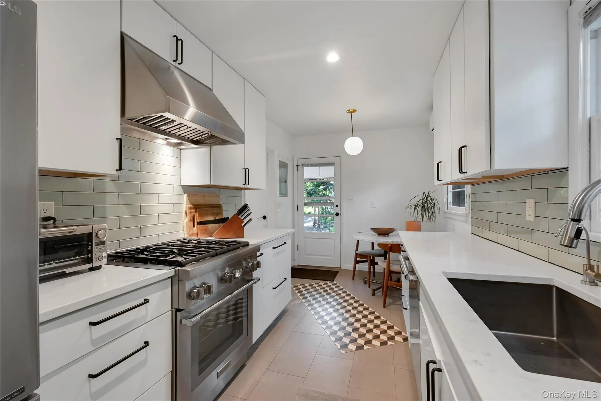 Kitchen with white cabinetry, under cabinet range hood, tasteful backsplash, appliances with stainless steel finishes, and recessed lighting Kitchen with white cabinetry, under cabinet range hood, tasteful backsplash, appliances with stainless steel finishes, and recessed lighting