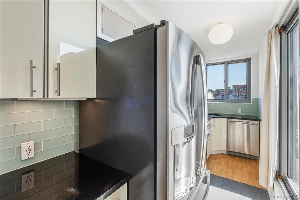 Kitchen featuring decorative backsplash, stainless steel appliances, white cabinetry, and light wood finished floors Kitchen featuring decorative backsplash, stainless steel appliances, white cabinetry, and light wood finished floors