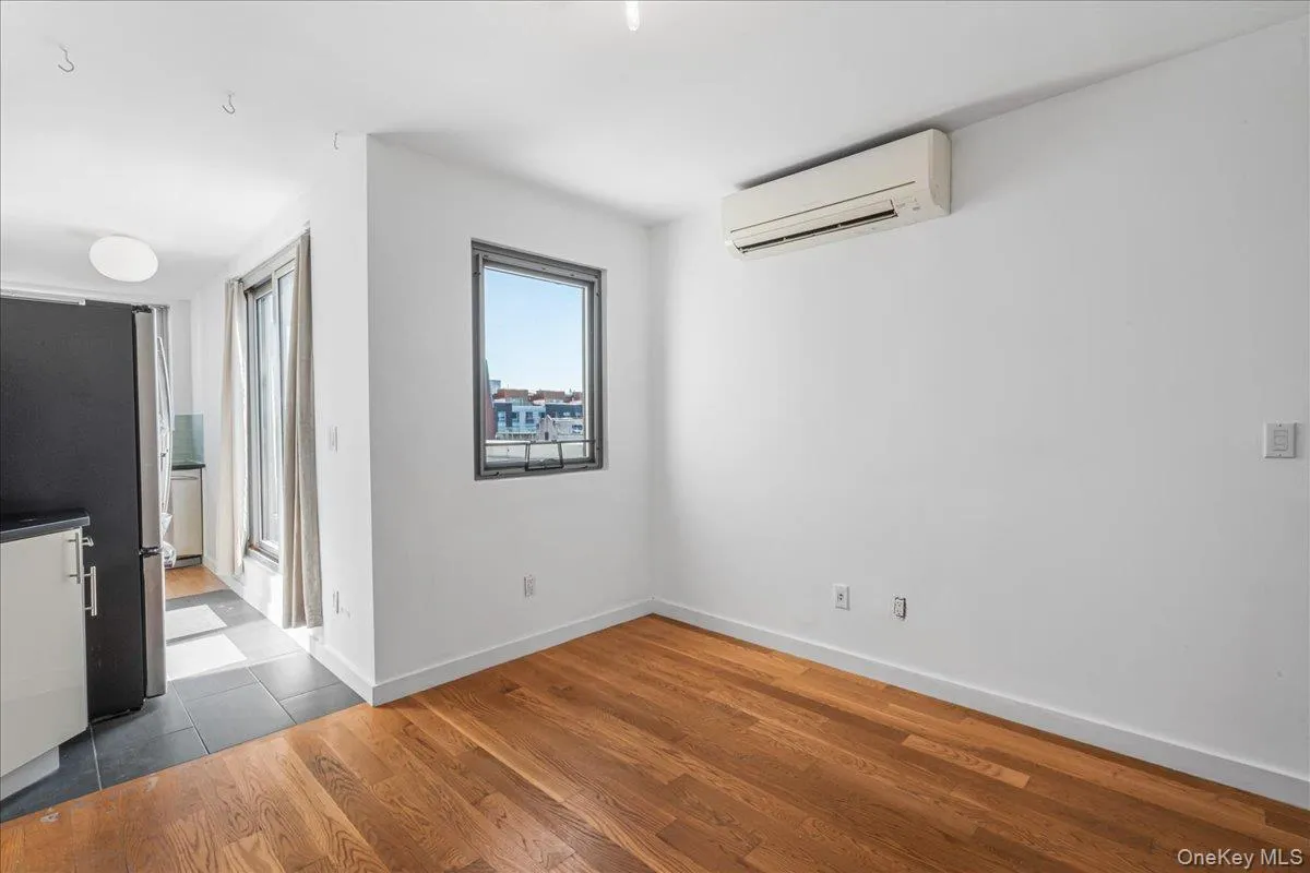 Unfurnished dining area featuring wood finished floors and a wall mounted air conditioner Unfurnished dining area featuring wood finished floors and a wall mounted air conditioner