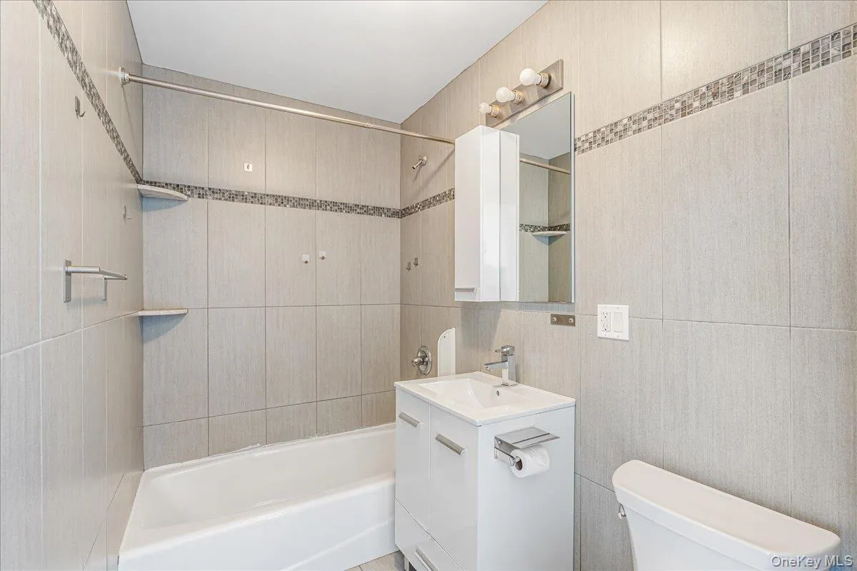 Full bath with bathing tub / shower combination, vanity, and tile walls Full bath with bathing tub / shower combination, vanity, and tile walls