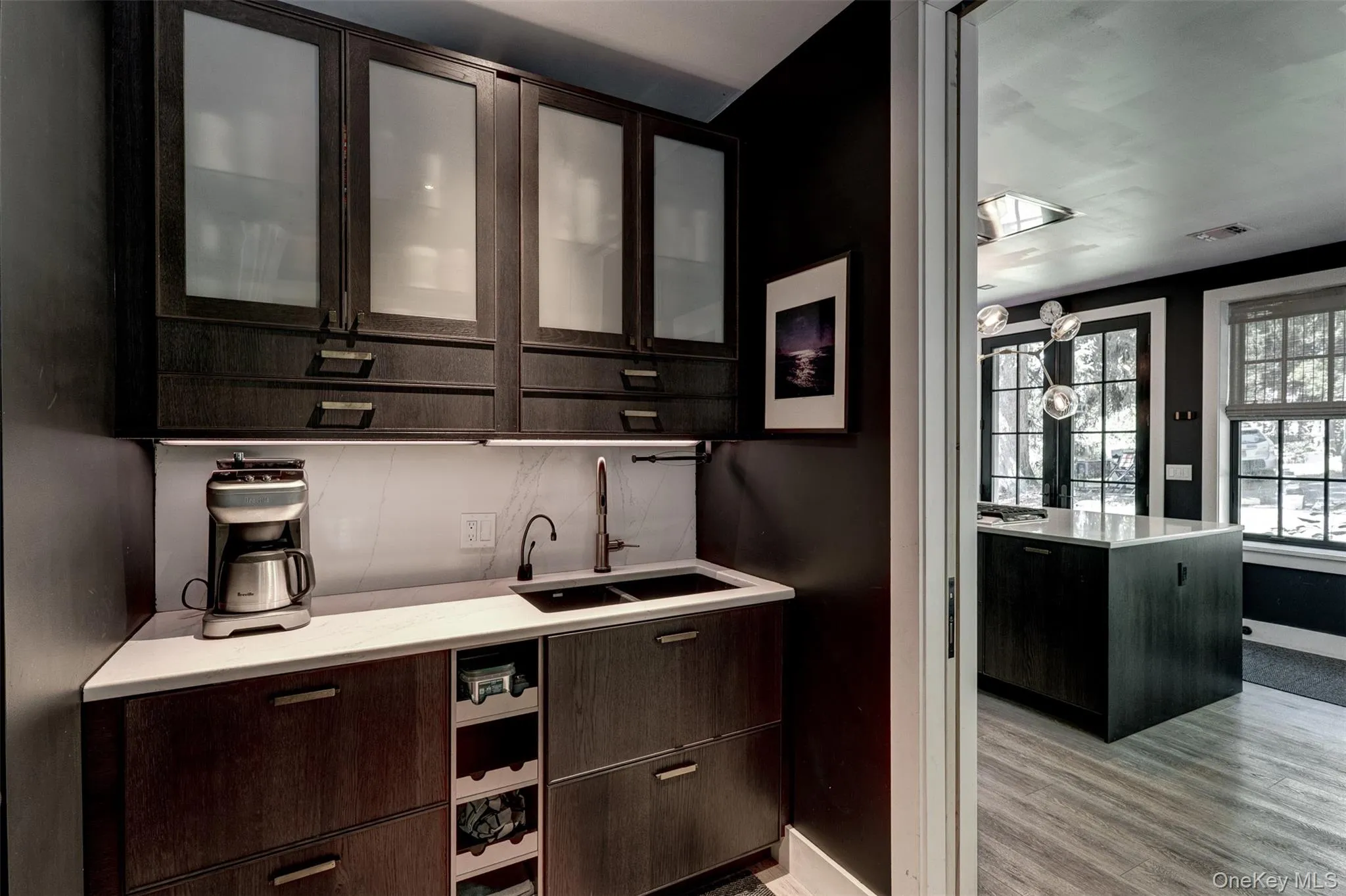 Bar area featuring dark brown cabinets, glass insert cabinets, light wood-style flooring, and modern cabinets Bar area featuring dark brown cabinets, glass insert cabinets, light wood-style flooring, and modern cabinets