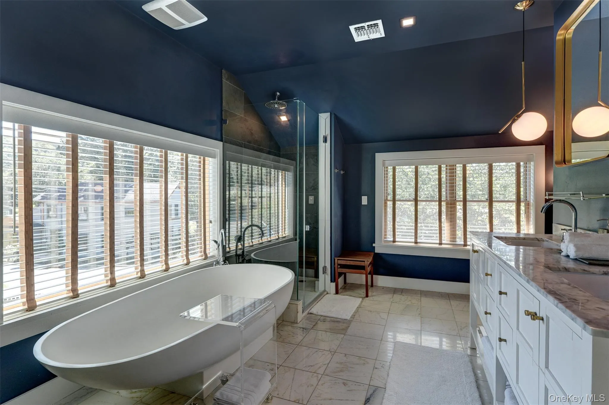 Full bath featuring a soaking tub, a stall shower, lofted ceiling, double vanity, and light marble finish floors Full bath featuring a soaking tub, a stall shower, lofted ceiling, double vanity, and light marble finish floors
