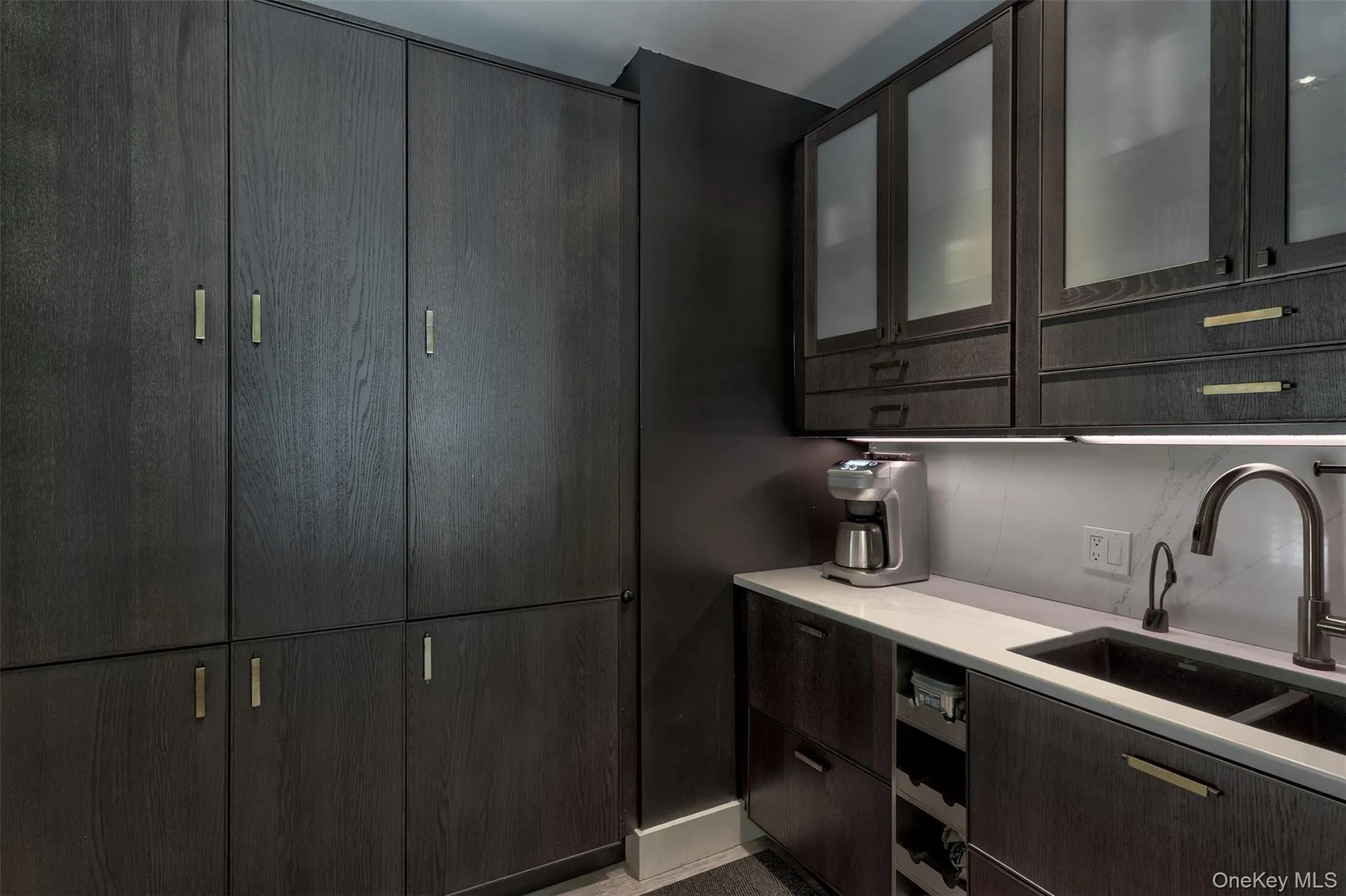 Kitchen featuring glass insert cabinets, dark brown cabinets, and modern cabinets Kitchen featuring glass insert cabinets, dark brown cabinets, and modern cabinets