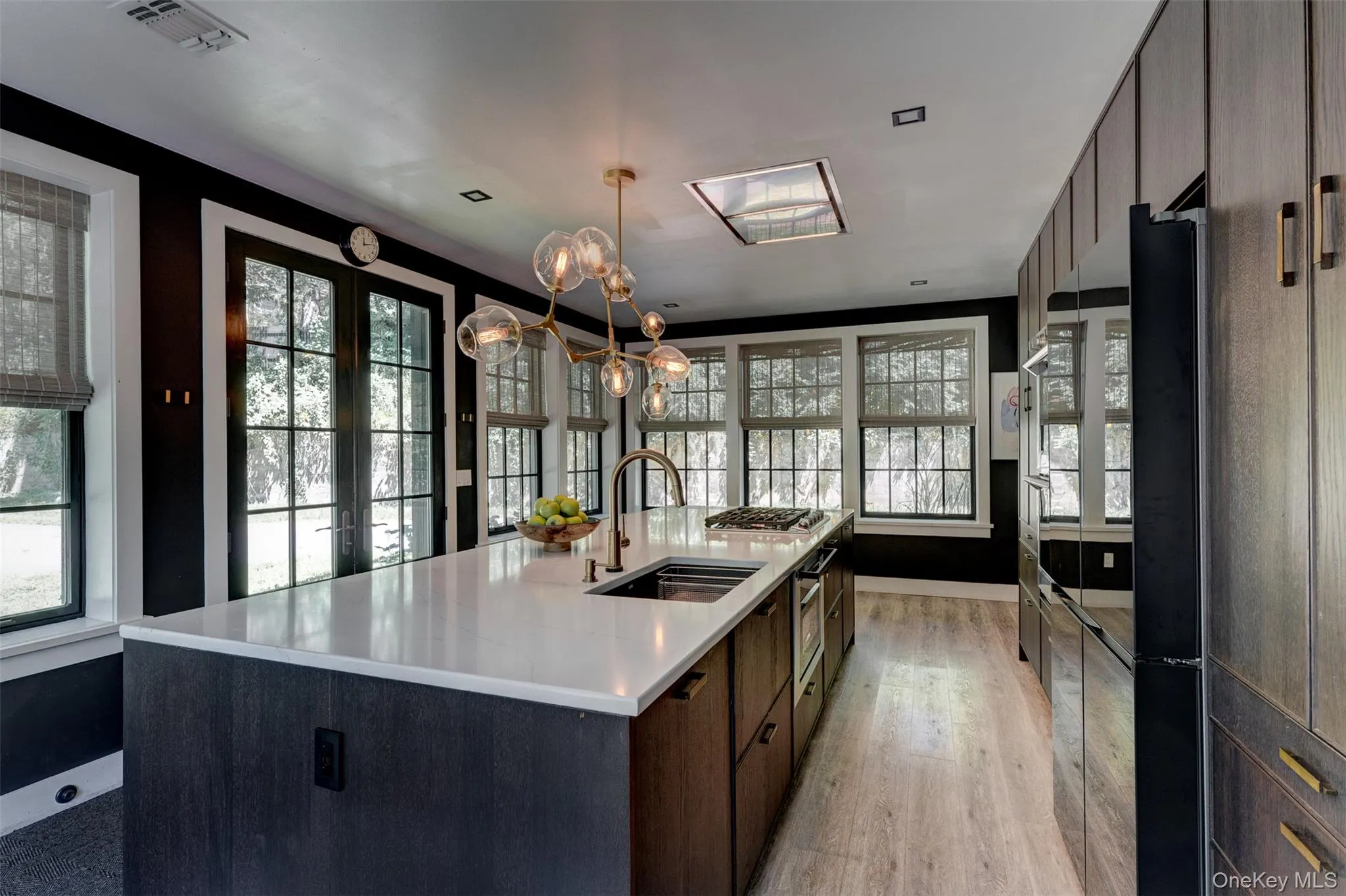 Kitchen with dark brown cabinetry, healthy amount of natural light, modern cabinets, and a large island Kitchen with dark brown cabinetry, healthy amount of natural light, modern cabinets, and a large island