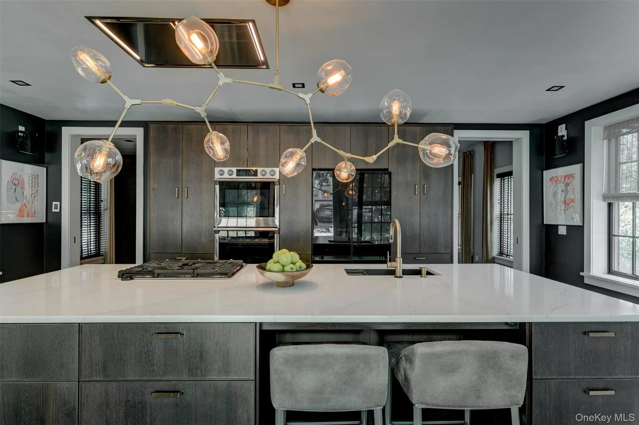 Kitchen featuring modern cabinets, appliances with stainless steel finishes, pendant lighting, light stone counters, and a large island Kitchen featuring modern cabinets, appliances with stainless steel finishes, pendant lighting, light stone counters, and a large island