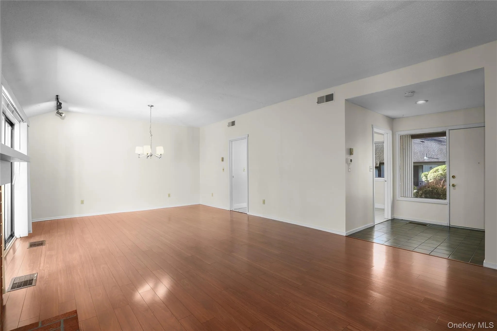 Living room featuring plenty of natural light, hardwood / wood-style floors, a chandelier, and vaulted ceiling Living room featuring plenty of natural light, hardwood / wood-style floors, a chandelier, and vaulted ceiling