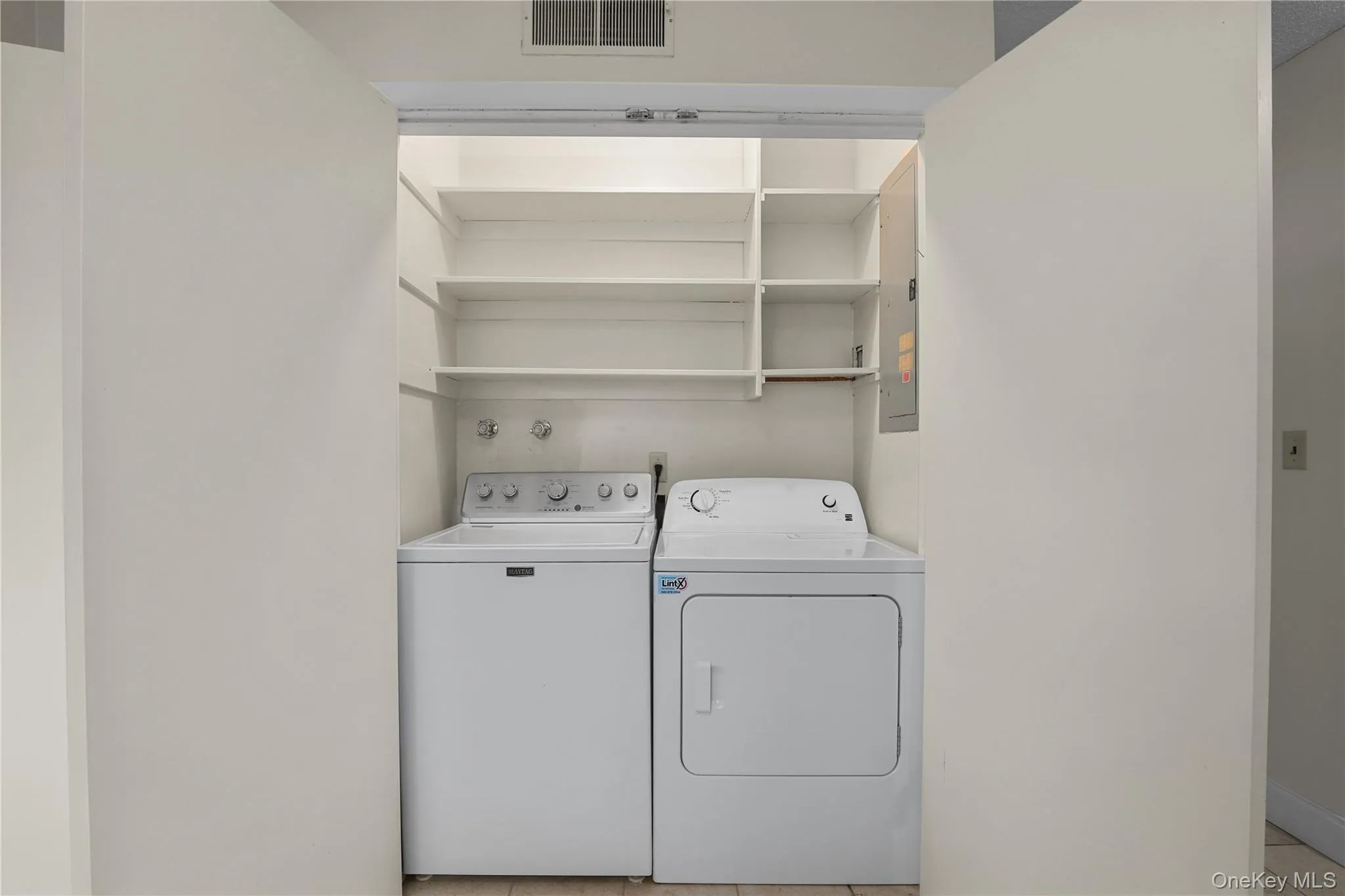 Laundry room with light tile patterned floors and independent washer and dryer Laundry room with light tile patterned floors and independent washer and dryer