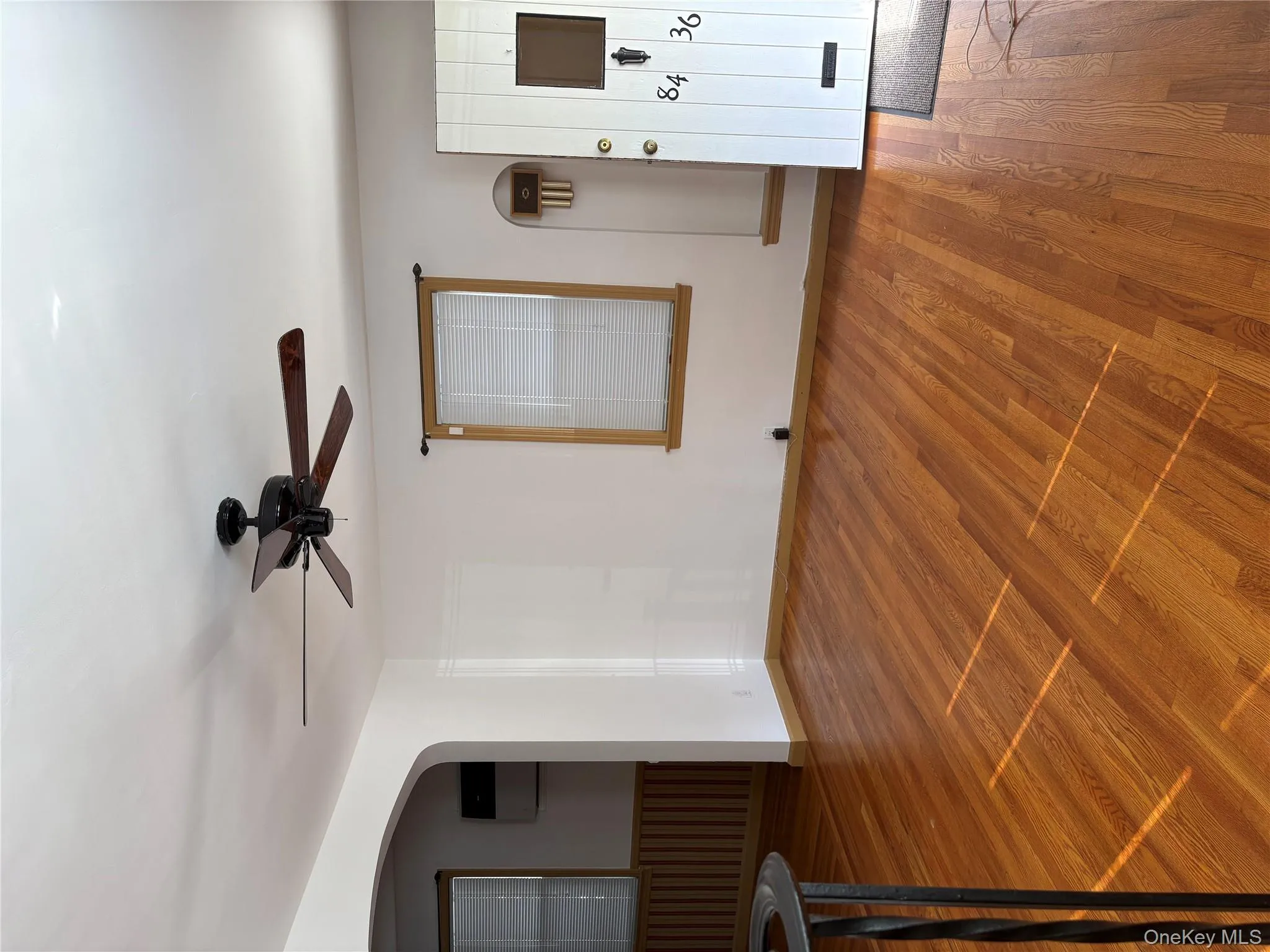 Unfurnished living room with arched walkways, a ceiling fan, wood finished floors, and a wainscoted wall Unfurnished living room with arched walkways, a ceiling fan, wood finished floors, and a wainscoted wall