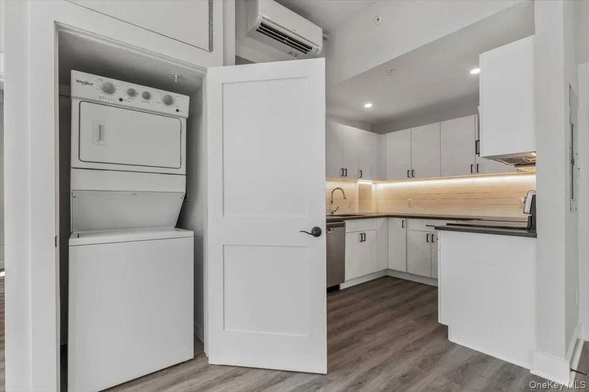 stacked washer / dryer, dark wood-style flooring, a wall mounted AC, and recessed lighting stacked washer / dryer, dark wood-style flooring, a wall mounted AC, and recessed lighting