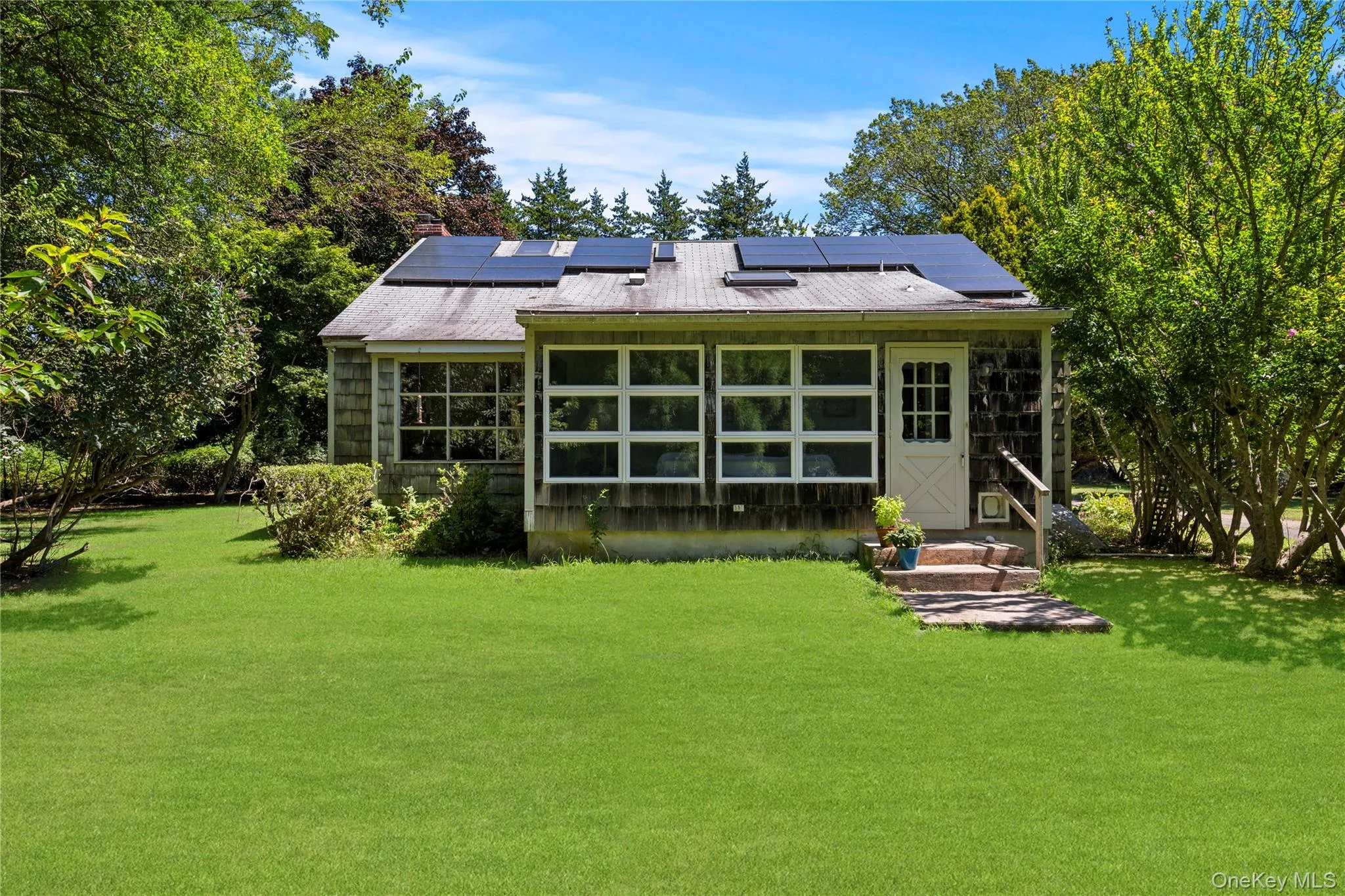 Back of property featuring solar panels, a yard leading to cottage Back of property featuring solar panels, a yard leading to cottage