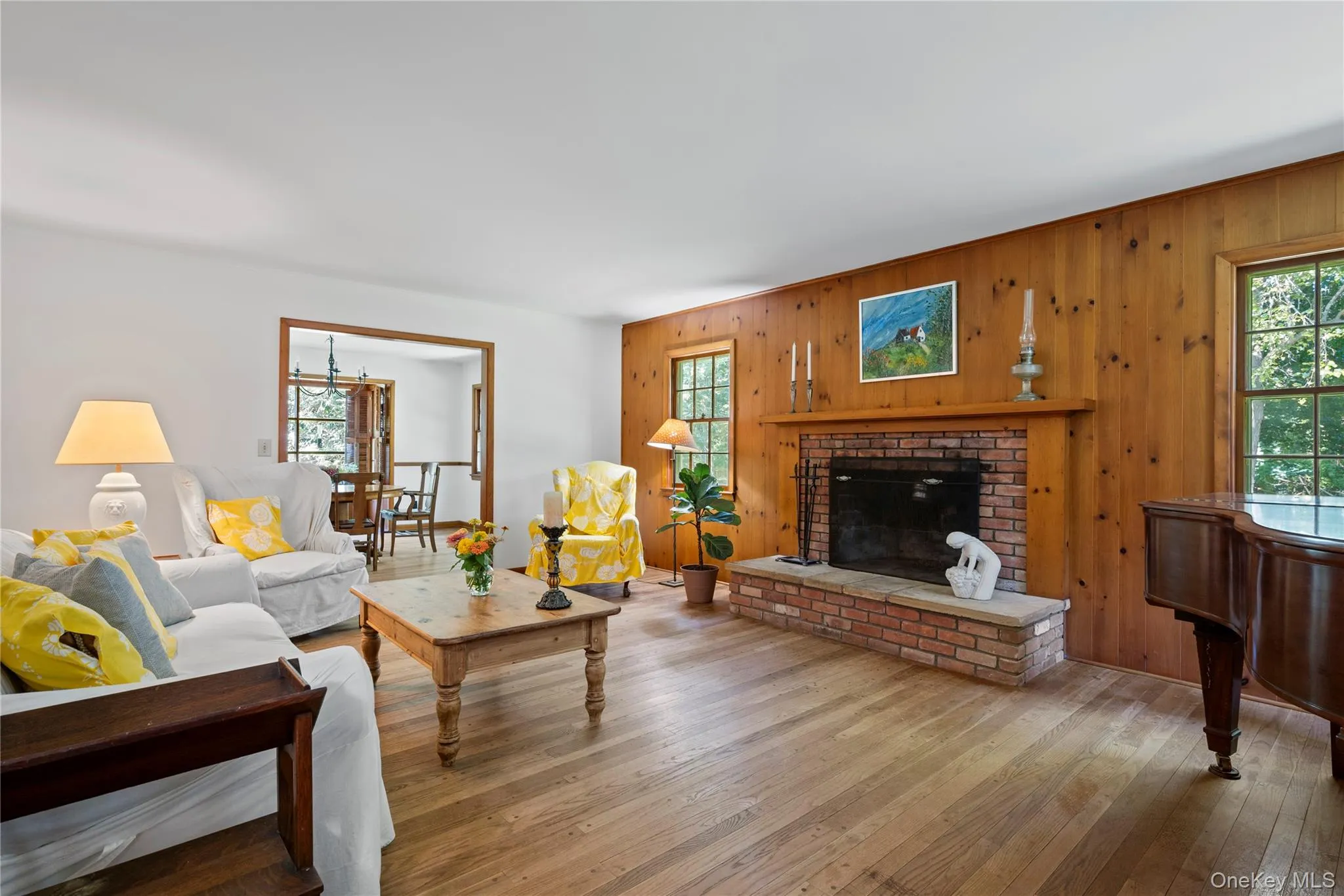 Living area featuring wood walls, a brick fireplace, and hardwood floors throughout Living area featuring wood walls, a brick fireplace, and hardwood floors throughout