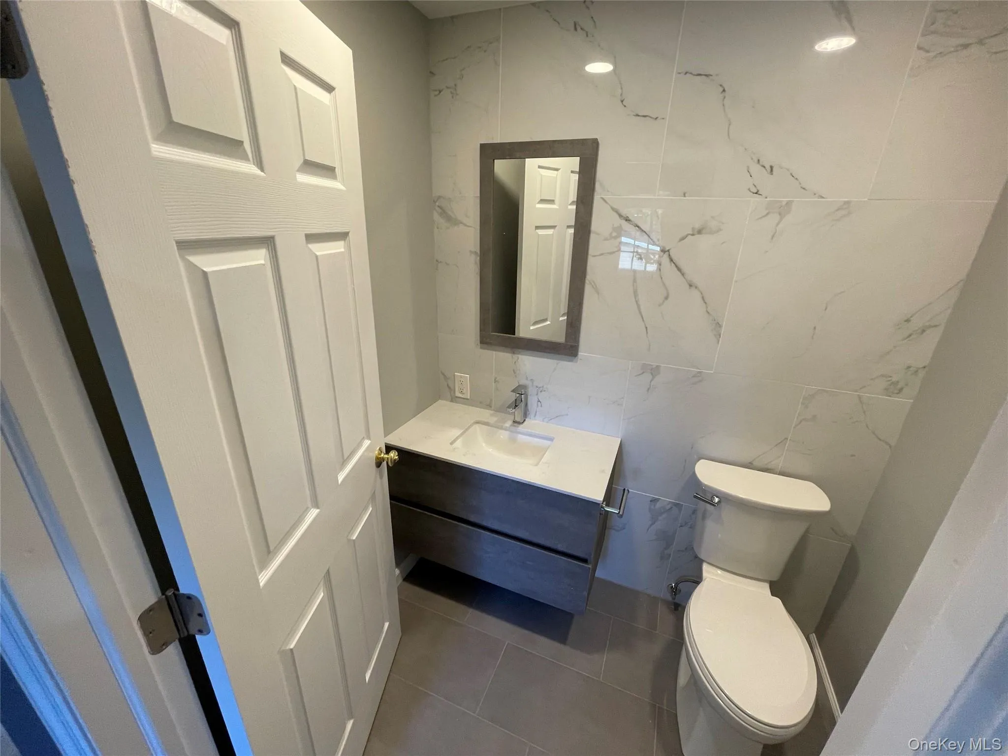 Second Half Bathroom featuring vanity, tile walls, and dark tile patterned floors on second floor. Second Half Bathroom featuring vanity, tile walls, and dark tile patterned floors on second floor.