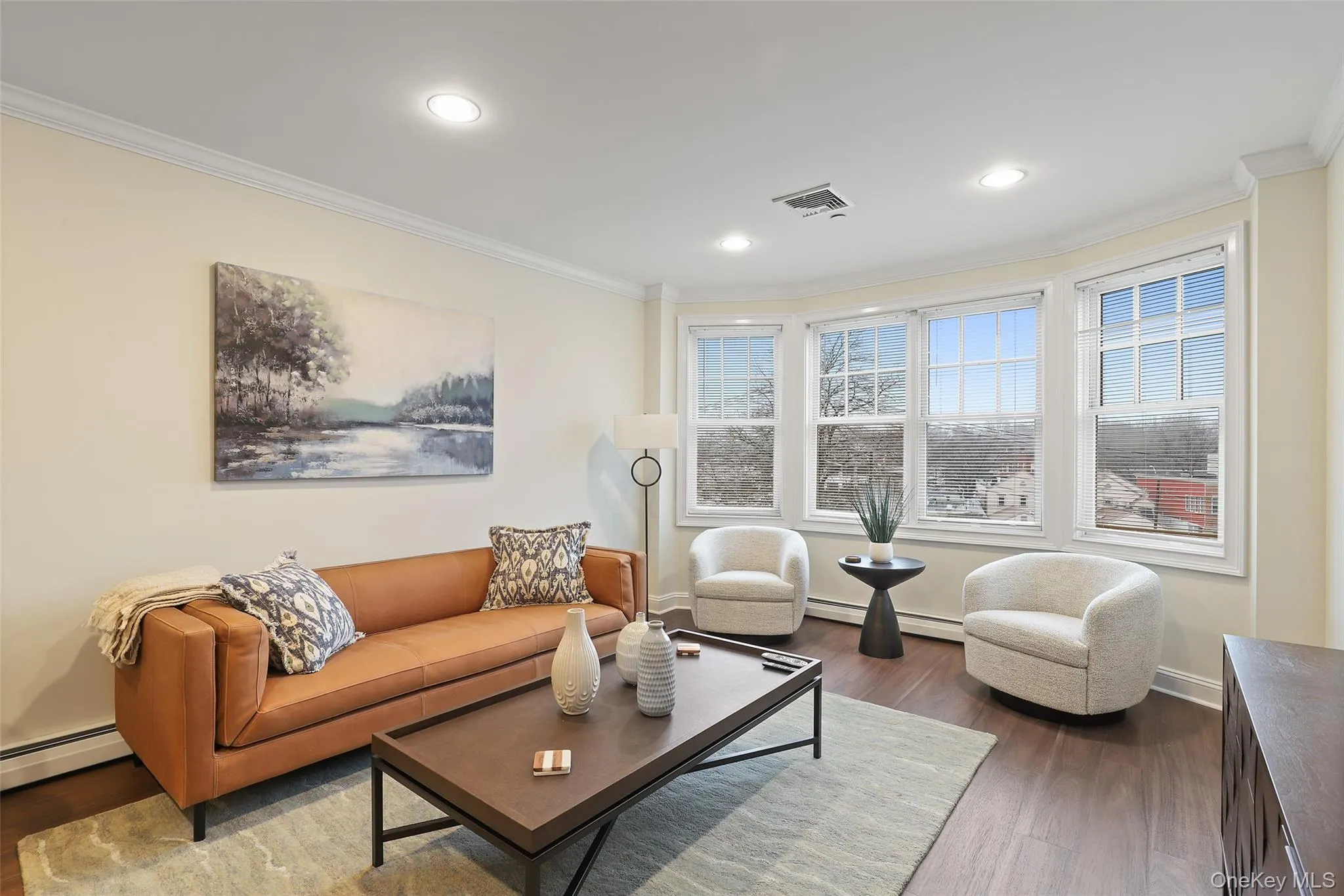 Living room featuring crown molding, dark wood-style flooring, a baseboard heating unit, and recessed lighting Living room featuring crown molding, dark wood-style flooring, a baseboard heating unit, and recessed lighting