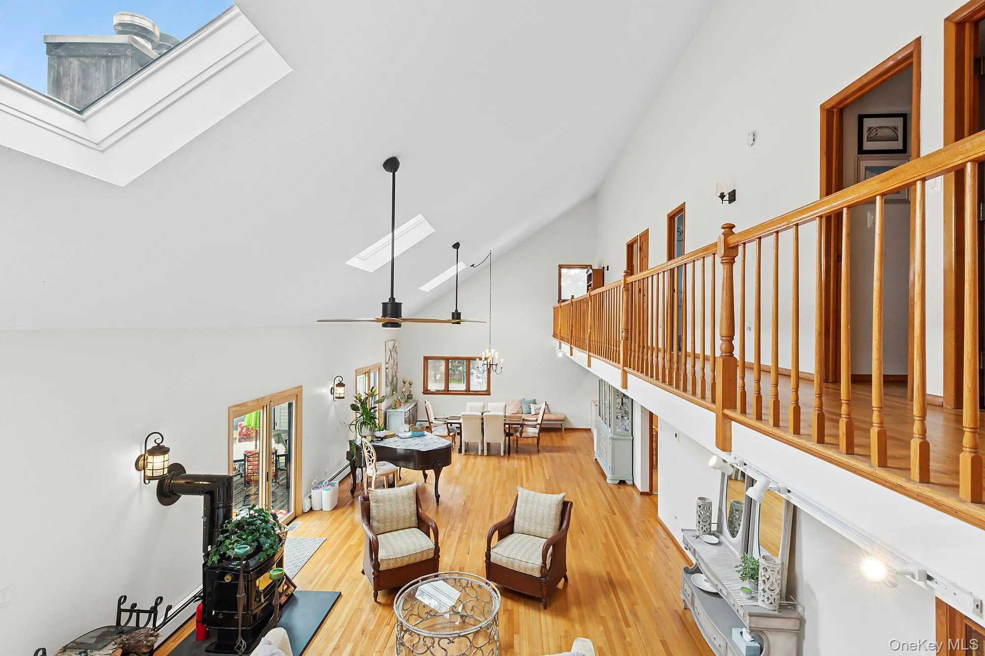 Living room featuring a skylight, high vaulted ceiling, and light wood-style floors Living room featuring a skylight, high vaulted ceiling, and light wood-style floors
