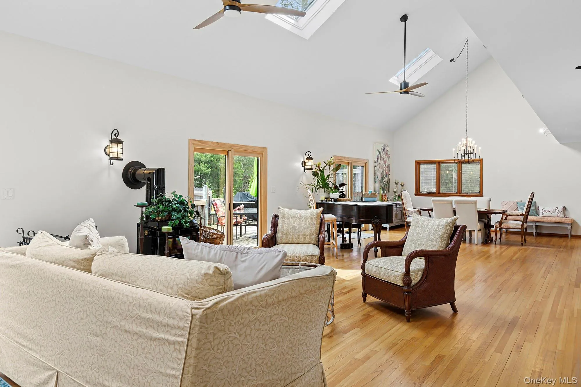 Living area with a ceiling fan, a skylight, high vaulted ceiling, hardwood / wood-style flooring, and a chandelier Living area with a ceiling fan, a skylight, high vaulted ceiling, hardwood / wood-style flooring, and a chandelier