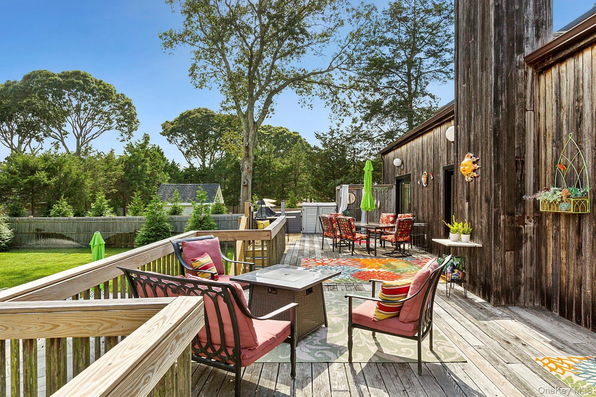 Wooden terrace featuring a fenced backyard, a fire pit, and outdoor dining area Wooden terrace featuring a fenced backyard, a fire pit, and outdoor dining area
