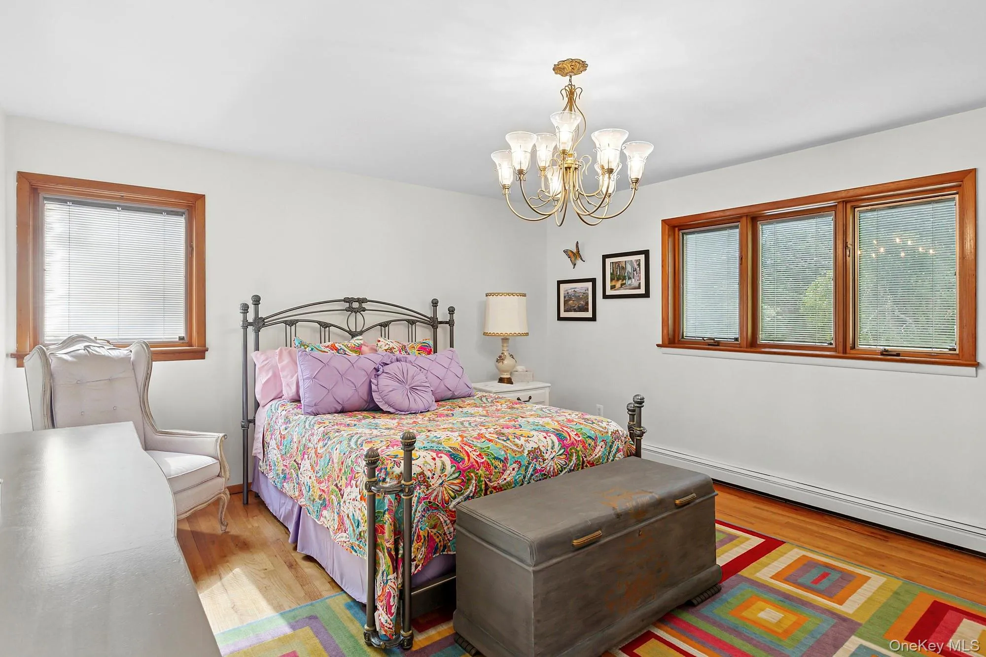 Bedroom with wood finished floors, a baseboard radiator, and a chandelier Bedroom with wood finished floors, a baseboard radiator, and a chandelier