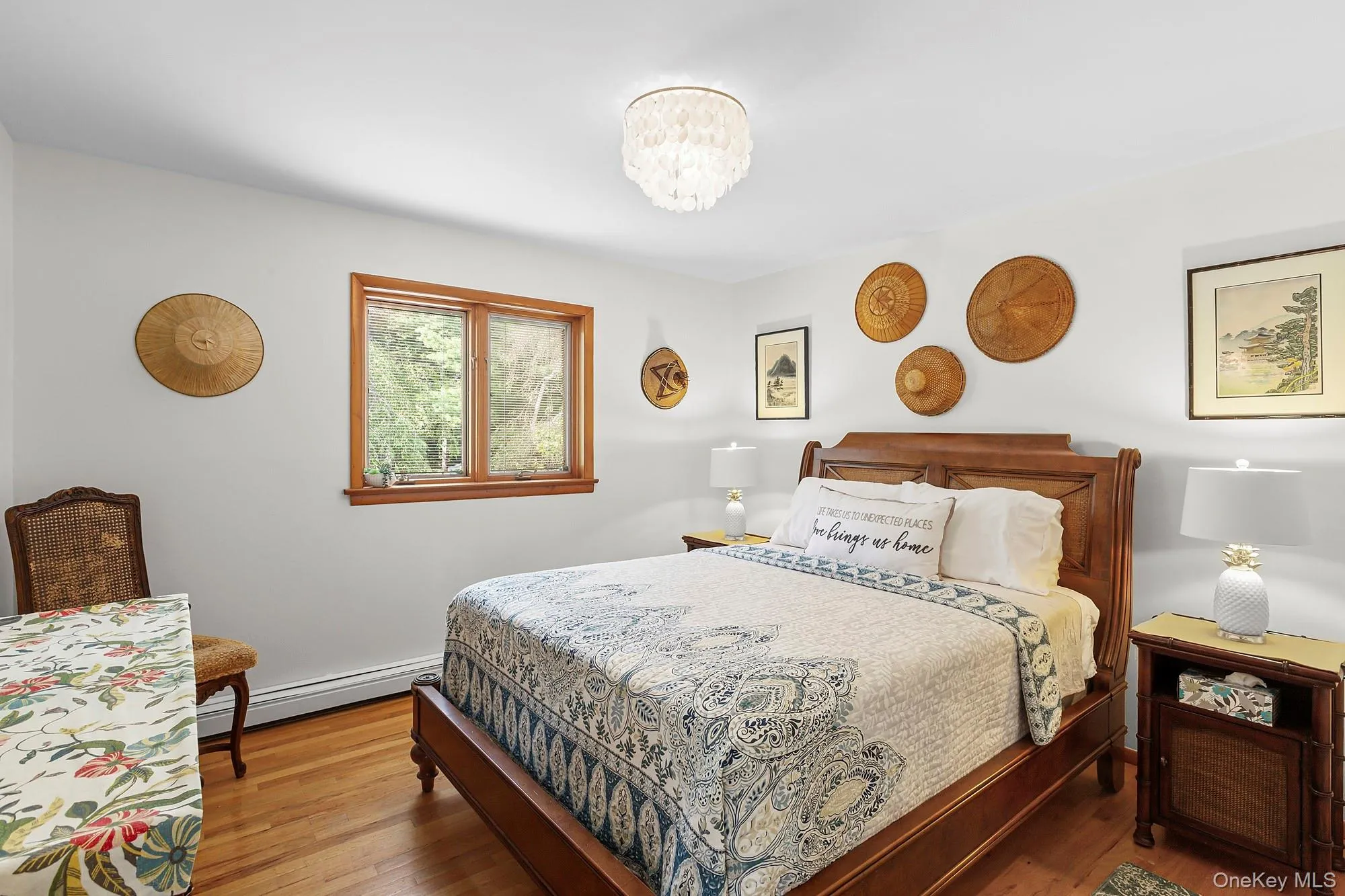 Bedroom with wood finished floors, baseboard heating, and a chandelier Bedroom with wood finished floors, baseboard heating, and a chandelier