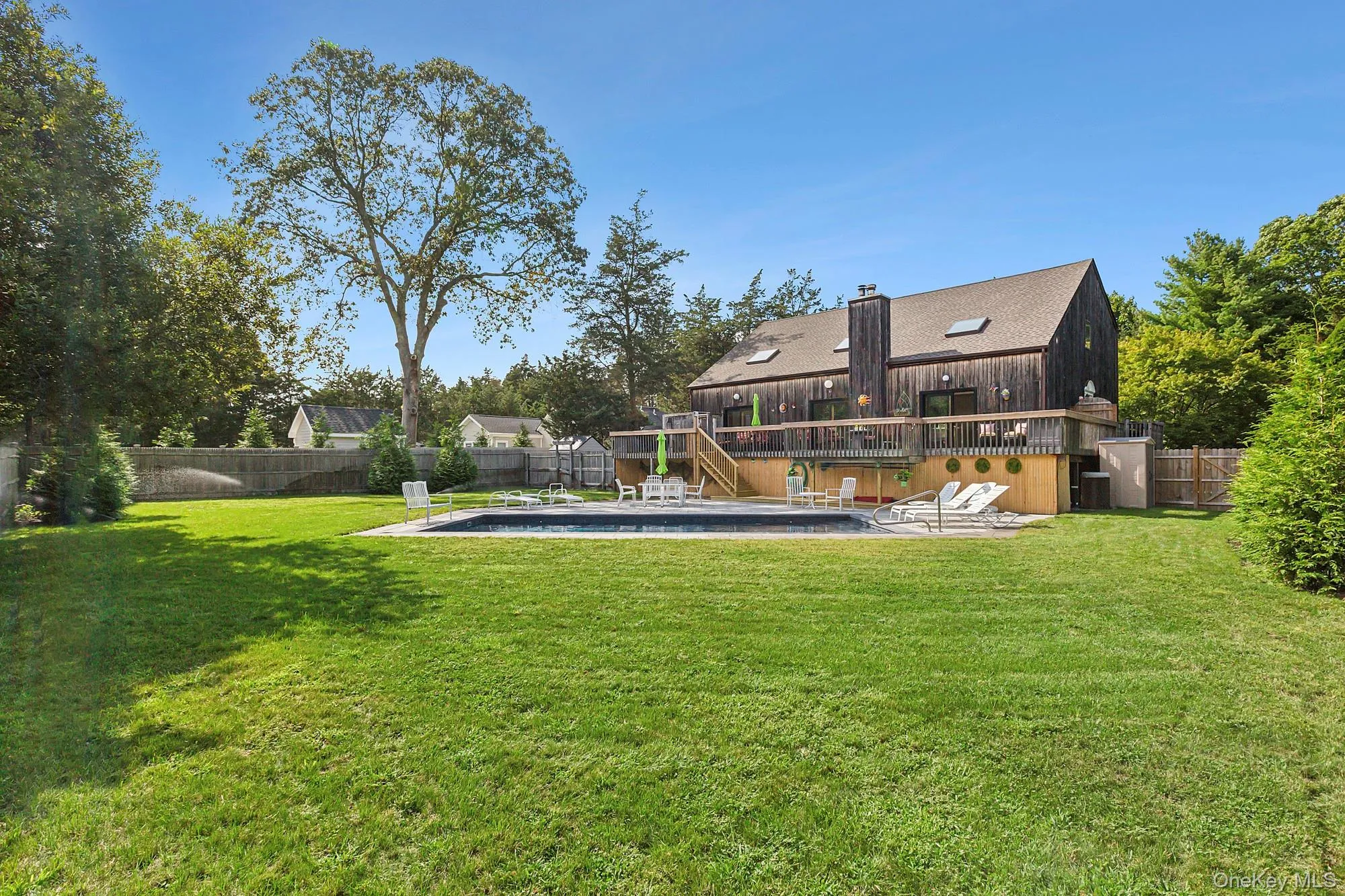 Fenced backyard featuring stairs, a patio, a pool, and a wooden deck Fenced backyard featuring stairs, a patio, a pool, and a wooden deck