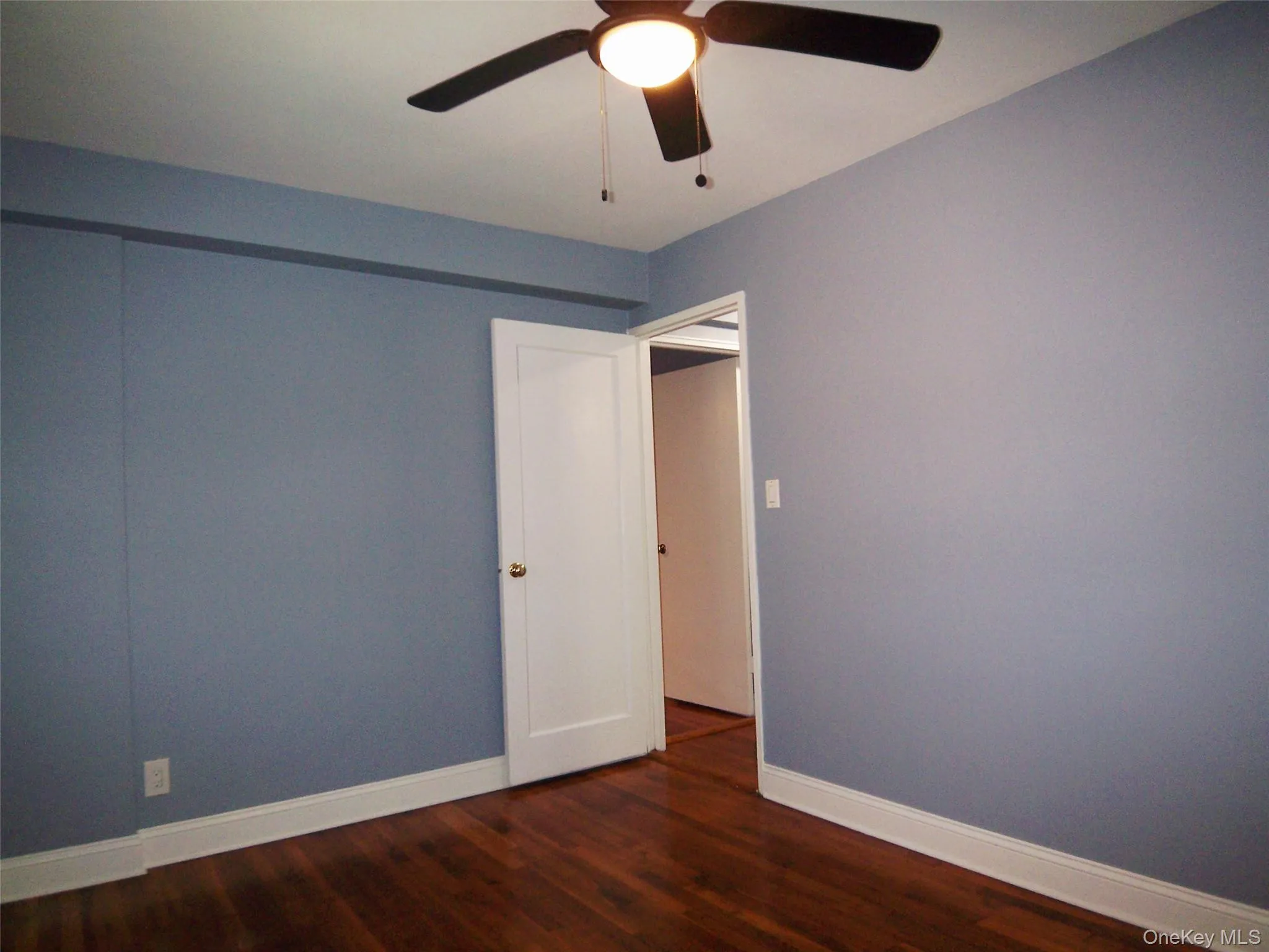 Unfurnished room featuring dark wood-style floors and a ceiling fan Unfurnished room featuring dark wood-style floors and a ceiling fan