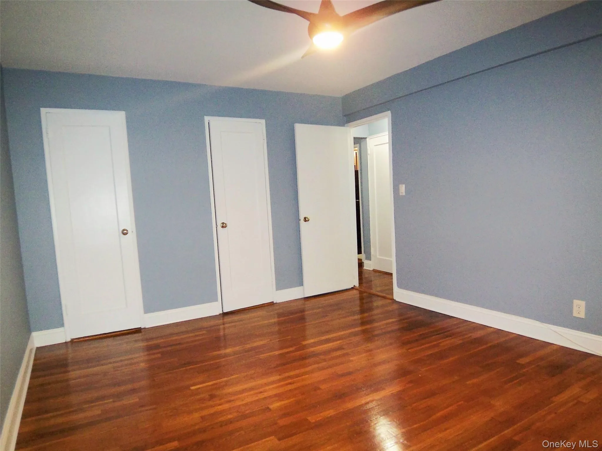 Unfurnished bedroom with dark wood-type flooring and baseboards Unfurnished bedroom with dark wood-type flooring and baseboards
